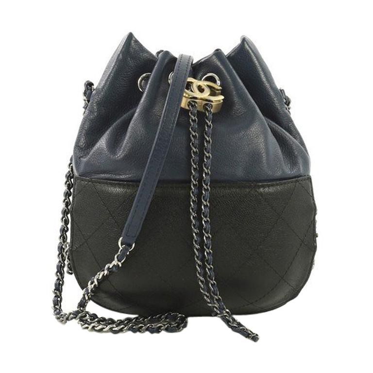 This Chanel Gabrielle Drawstring Bag Quilted Calfskin Small, crafted in blue and black quilted calfskin leather, features a woven-in leather chain strap with leather pad, drawstring with CC logo accent, and gunmetal and gold-tone hardware. Its