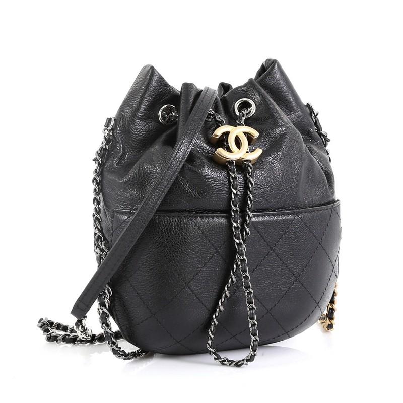 This Chanel Gabrielle Drawstring Bag Quilted Calfskin Small, crafted in black quilted calfskin leather, features woven-in leather chain strap with leather pad, drawstring with CC logo accent, and gunmetal and gold-tone hardware. Its drawstring