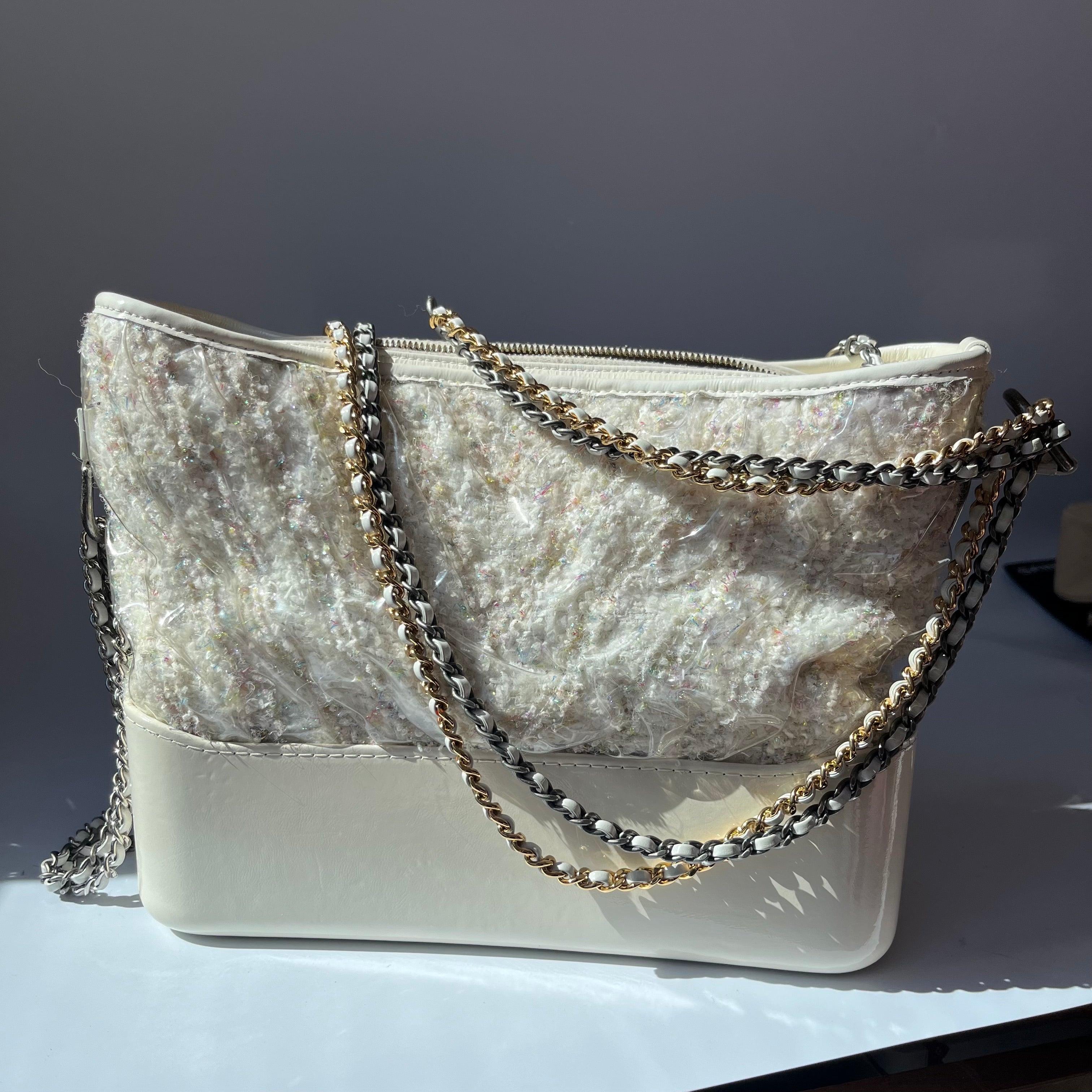 Chanel Gabrielle Hobo Medium White Tweed with PVC, 2018-2019

  Designed by Lagerfeld, the form of the Gabrielle line of bags was inspired by vintage binocular cases and virtual reality headsets. A relaxed hobo, the Gabrielle embodied an