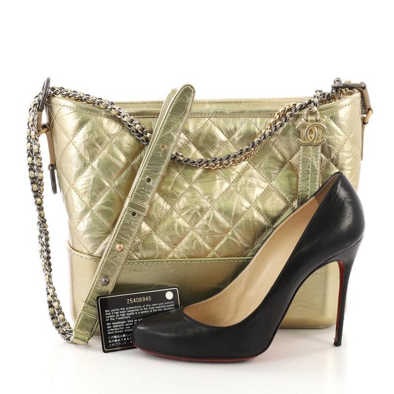This Chanel Gabrielle Hobo Quilted Aged Calfskin Medium, crafted from gold quilted aged calfskin leather, features gradient woven-in leather chain with leather pads and gold, silver and gunmetal-tone hardware. Its zip closure opens to a red fabric