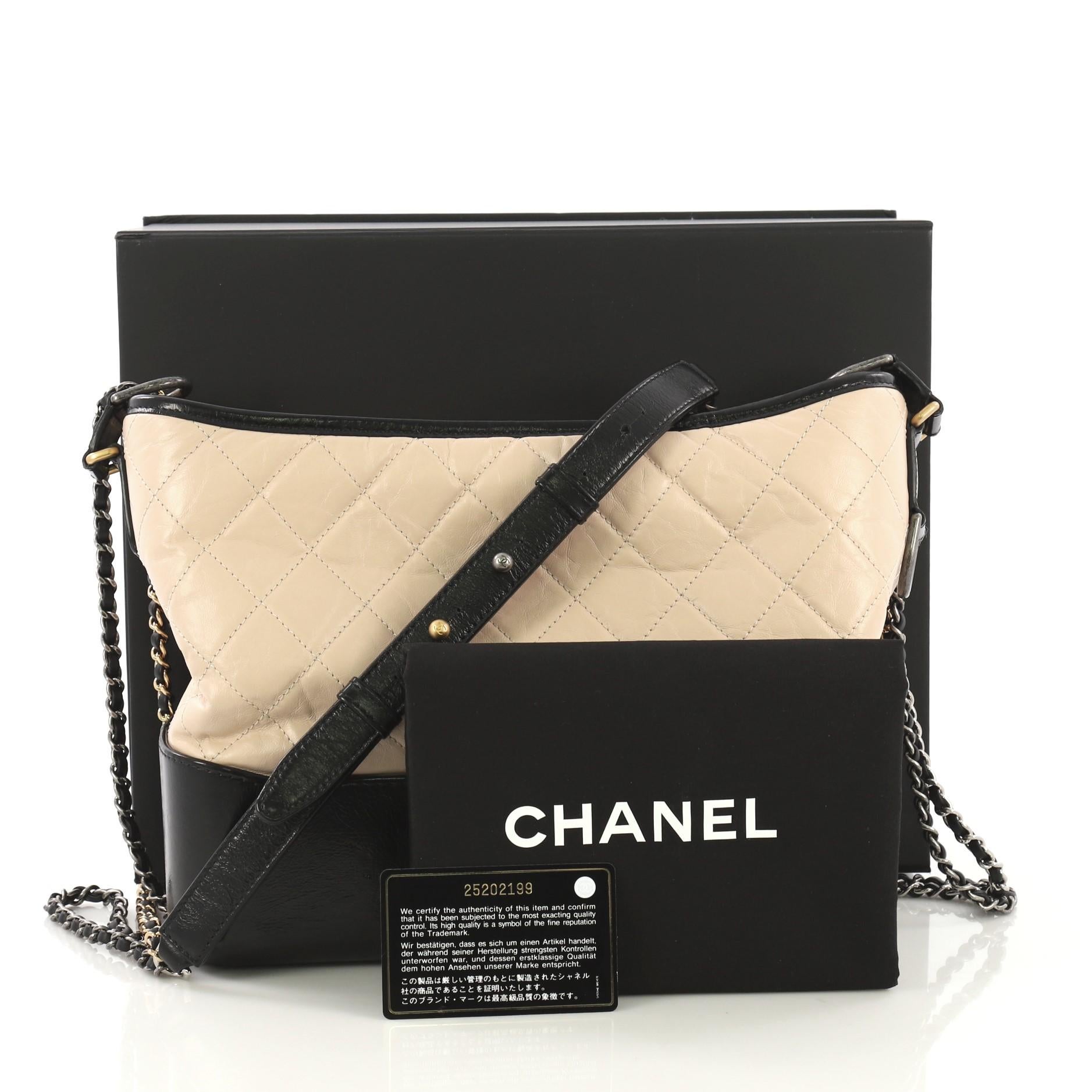 This Chanel Gabrielle Hobo Quilted Aged Calfskin Medium, crafted from black and nude quilted aged calfskin, features woven-in leather chain with leather pad, leather zip pull with CC logo, and aged gold and silver-tone hardware. Its zip closure
