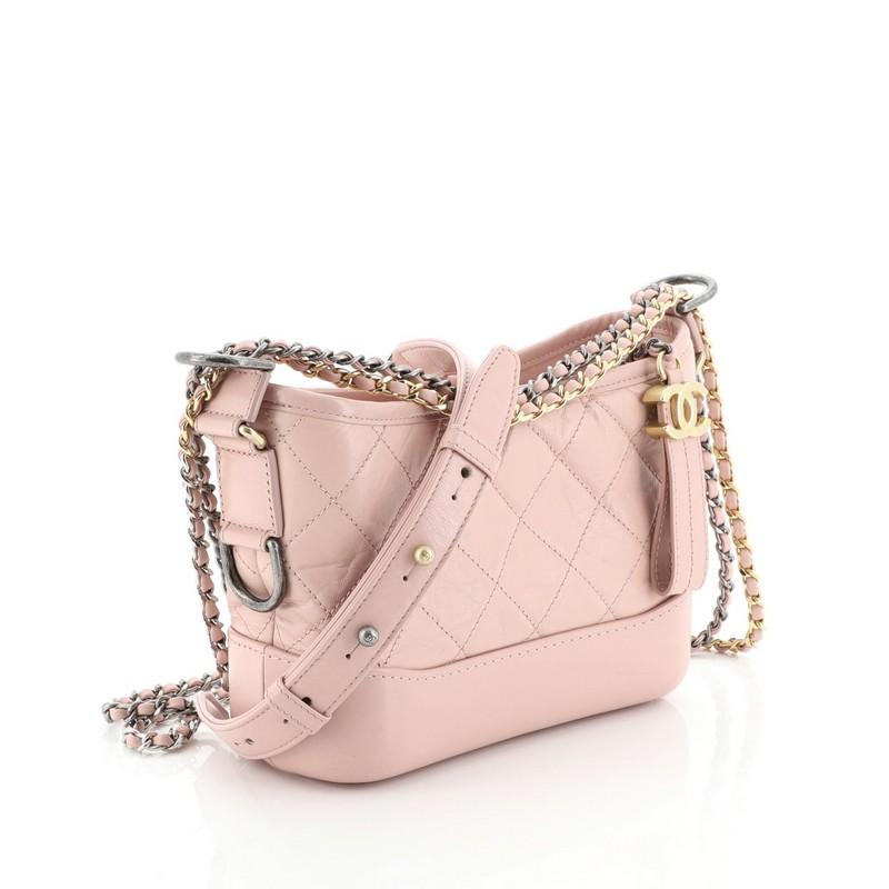 This Chanel Gabrielle Hobo Quilted Aged Calfskin Small, crafted from pink quilted aged calfskin leather, features woven-in leather chain strap with leather pad, leather zip pull with CC logo, and aged silver, and gold-tone hardware. Its zip closure