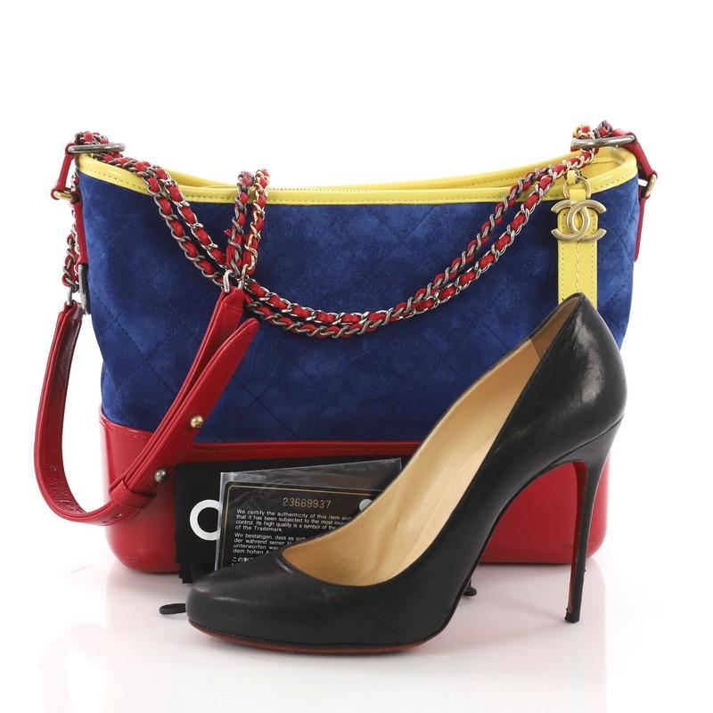 This Chanel Gabrielle Hobo Quilted Suede Medium, crafted from blue quilted suede and red leather, features woven-in leather chain with leather pads, leather zip pull with CC logo, and aged silver and gold-tone hardware. Its zip closure opens to a