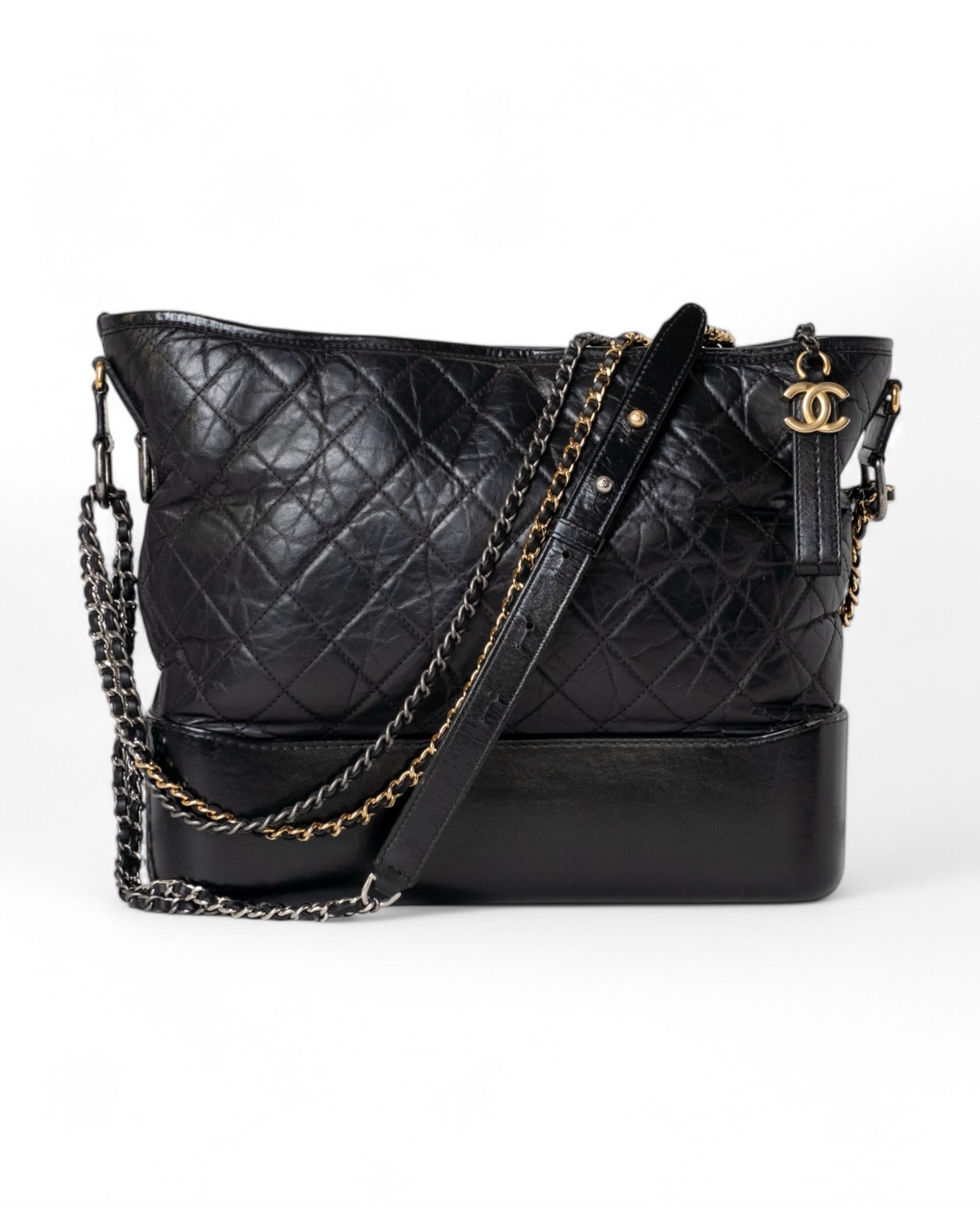 Chanel signature bag, Gabrielle model, size XL, made of black leather with silver/gold hardware. Equipped with a top zipper closure, internally lined with red canvas, very roomy. Equipped with a leather shoulder strap and slide braided chain, so the