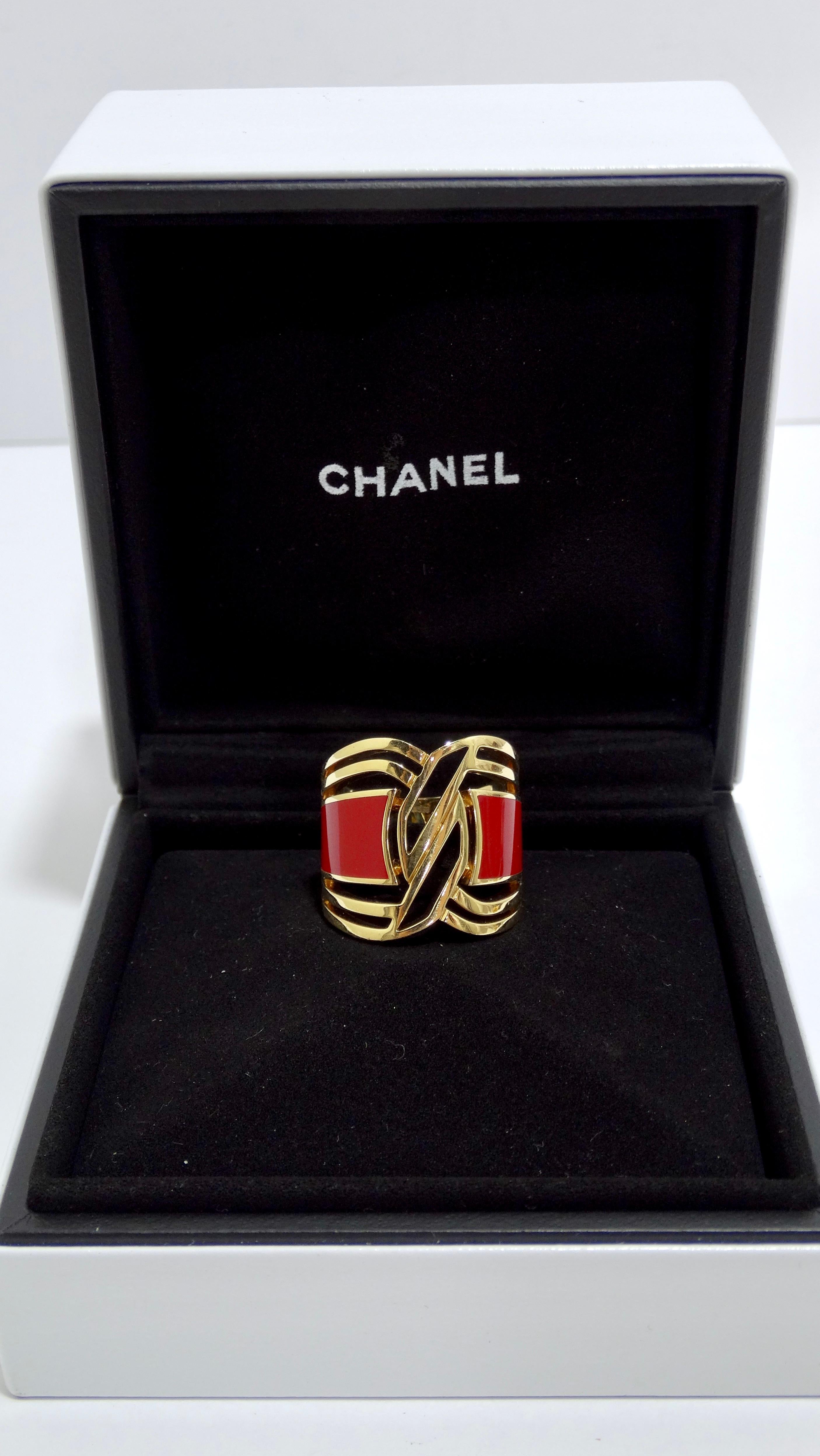 This Chanel ring gives a modern flair to the brand's ever-so-classic designs. This ring features geometrical cut outs made of 18k gold and features a HyCeram red band. HyCeram is a hard-wearing, scratch-resistant new material that mimics the