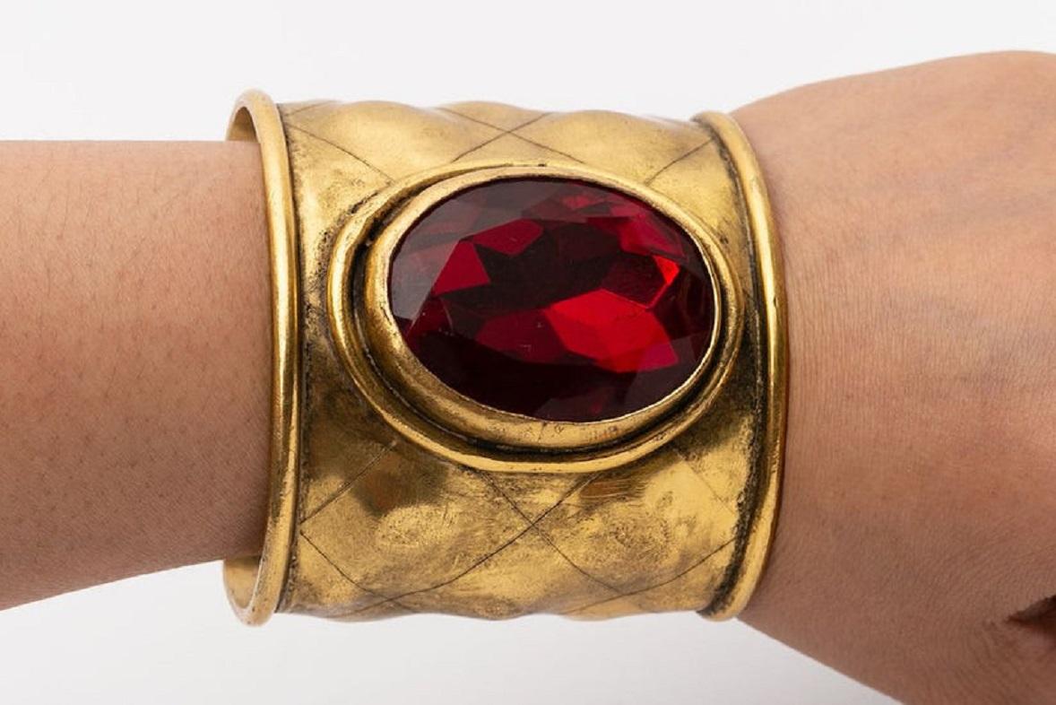 Chanel (Made in France) Cuff bracelet in hammered gilded metal decorated with a ruby rhinestone.

Additional information:

Dimensions: 
Circumference: 15.5 cm (6.1