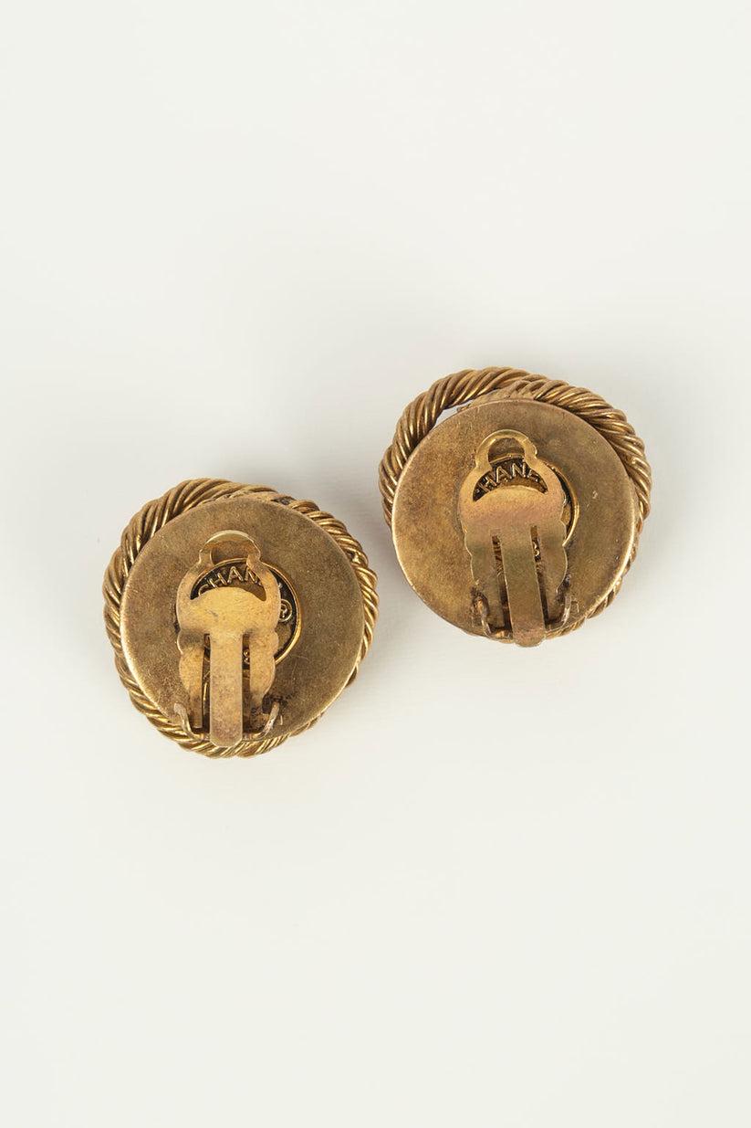 Chanel - (Made in France) Ohrringe aus vergoldetem Metall mit einem perlmuttfarbenen Cabochon in der Mitte. Collection'S 1984.

Zusätzliche Informationen:

Abmessungen: 
Ø 2,5 cm

Zustand: Guter Zustand

Verkäufer Ref Nummer: BOB53