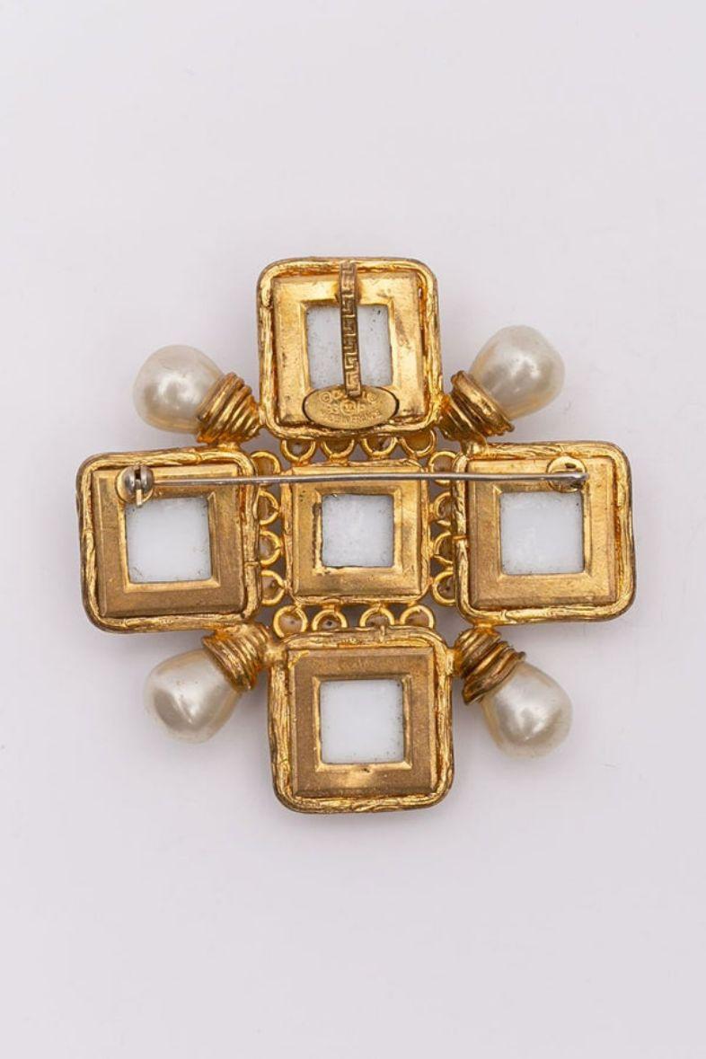Chanel (Made in France) Gilted metal and glass paste brooch representing a cross. It carry an hook at the back to be worn as a pendant. 
Spring - Summer 1993 collection.

Additional information:

Dimensions: 
7 cm (2.76 in) x 7 cm (2.76