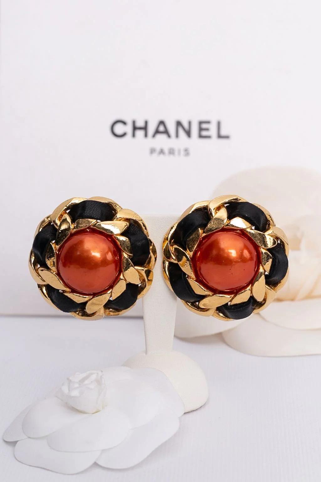 Chanel - (Made in France) Gilted metal clip-on earrings entwined with black leather and centered with an orange cabochon. 2cc5 Collection.

Additional information:

Dimensions: 
Ø 4.5 cm (Ø 1.77