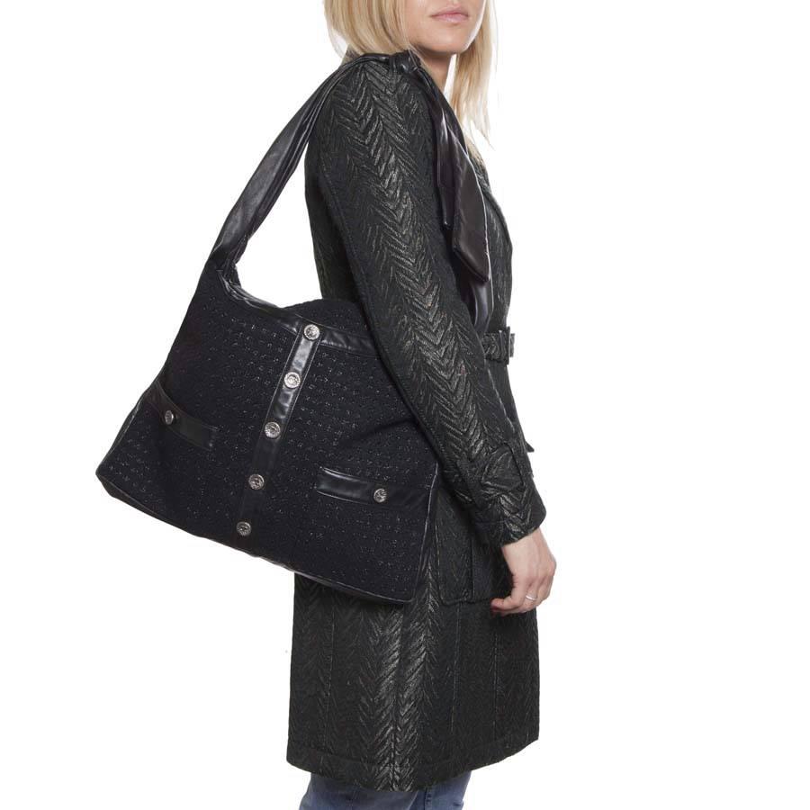 Chanel Girl bag in black and shiny tweed and lambskin. Large model with a pocket at the front closed by snap. Buttons are hammered in mat silver metal. Zip closure. 
The interior is in black canvas with a large zipped pocket. 
Included : Hologram: