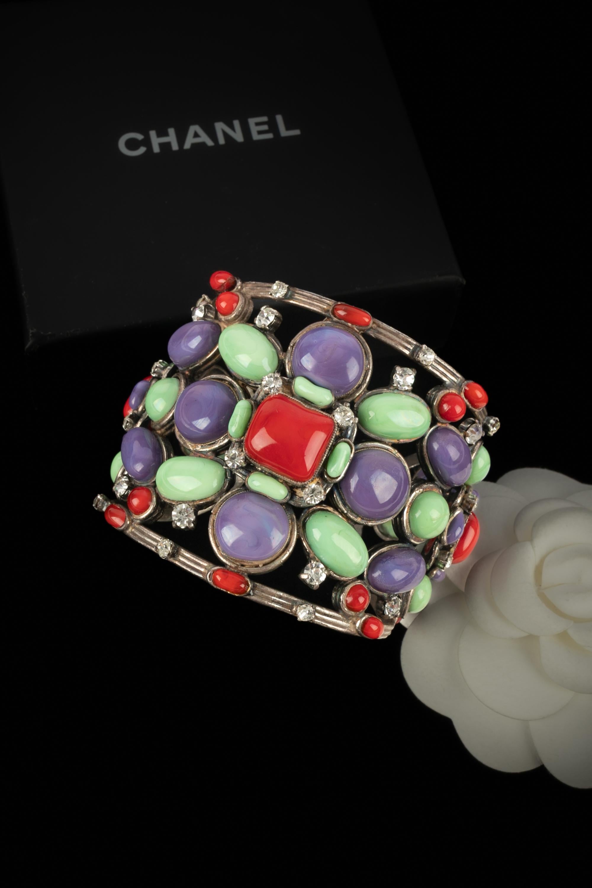 CHANEL - (Fabriqué en France) Bracelet manchette ajouré en métal argenté avec strass et pâte de verre verte, rouge et violette.

Condit :
Bon état

Dimensions :
Circonférence : 13,5 cm - Ouverture : 2,5 cm

SKU:BRAB26