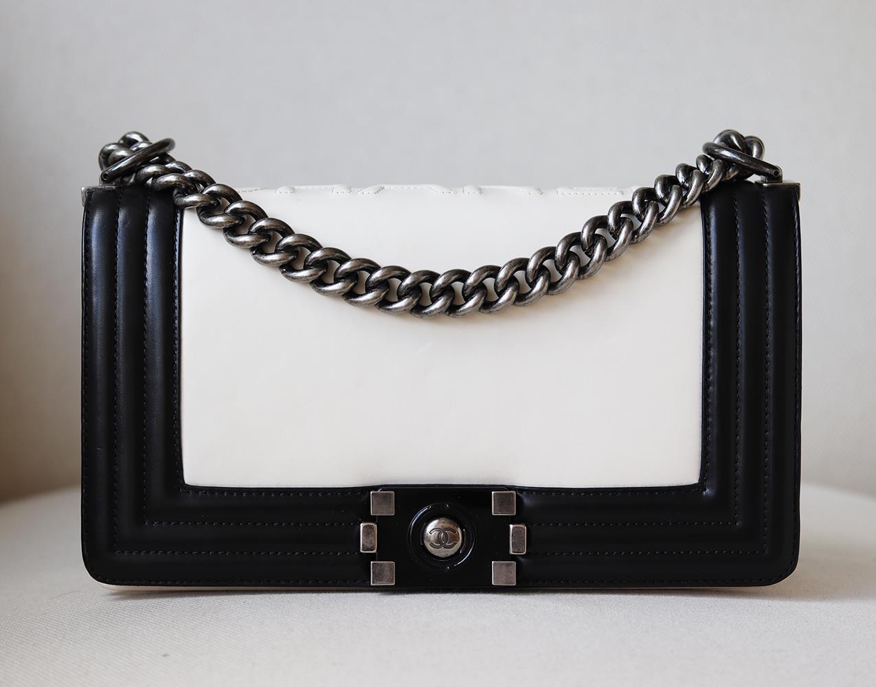 Chanel Glazed Calfskin Leather Boy Flap Bag has been hand-finished by skilled artisans in the label's workshop. Boasting smooth black and ivory calfskin-leather exterior, this design is accented with silver-toned and black calfskin-leather chain