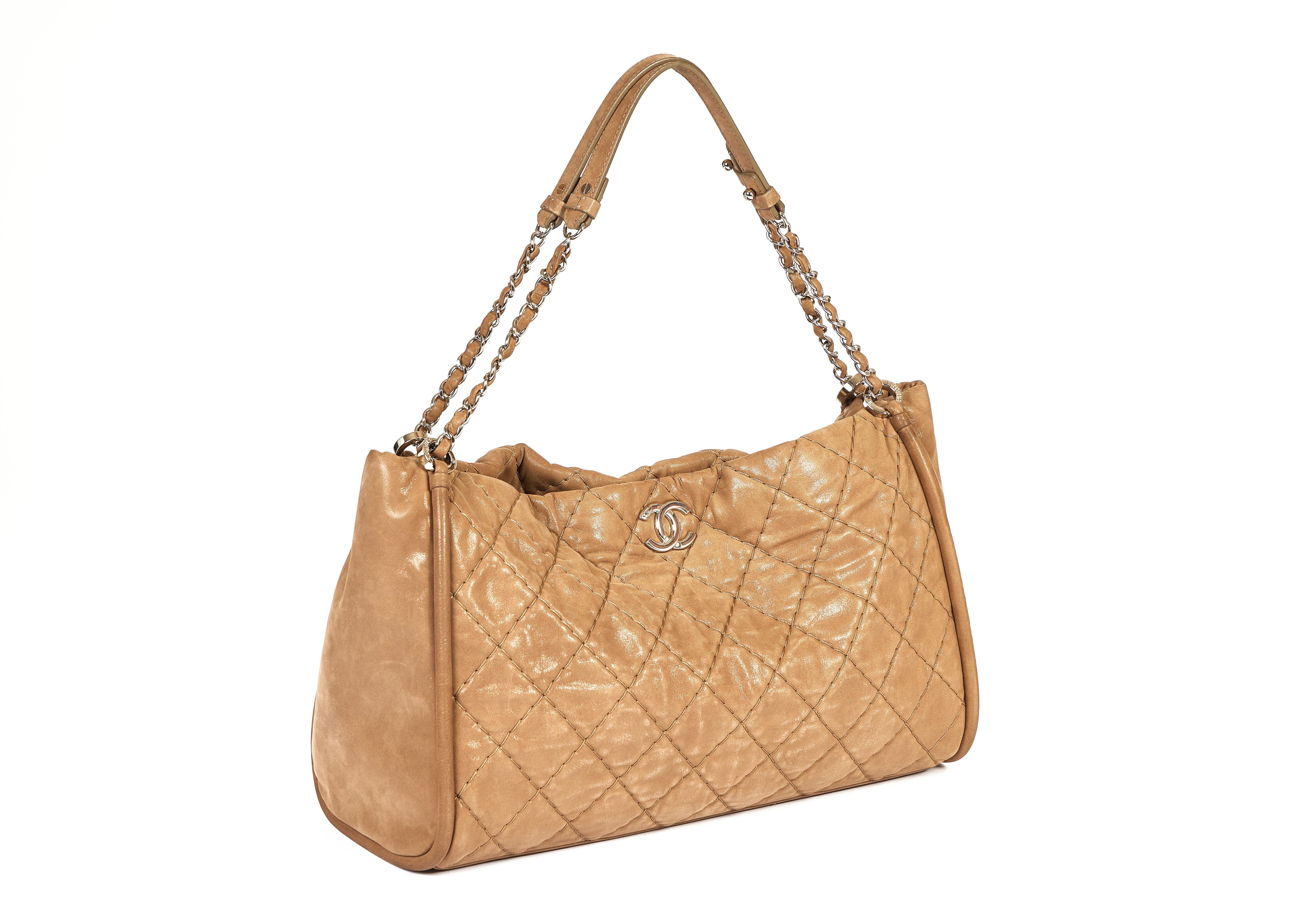 Questa bellissima borsa a tracolla Chanel di colore beige è realizzata in pelle scamosciata trapuntata smaltata e presenta un motivo trapuntato cucito. Il doppio logo CC in argento è applicato sul davanti e si abbina perfettamente alle catene a