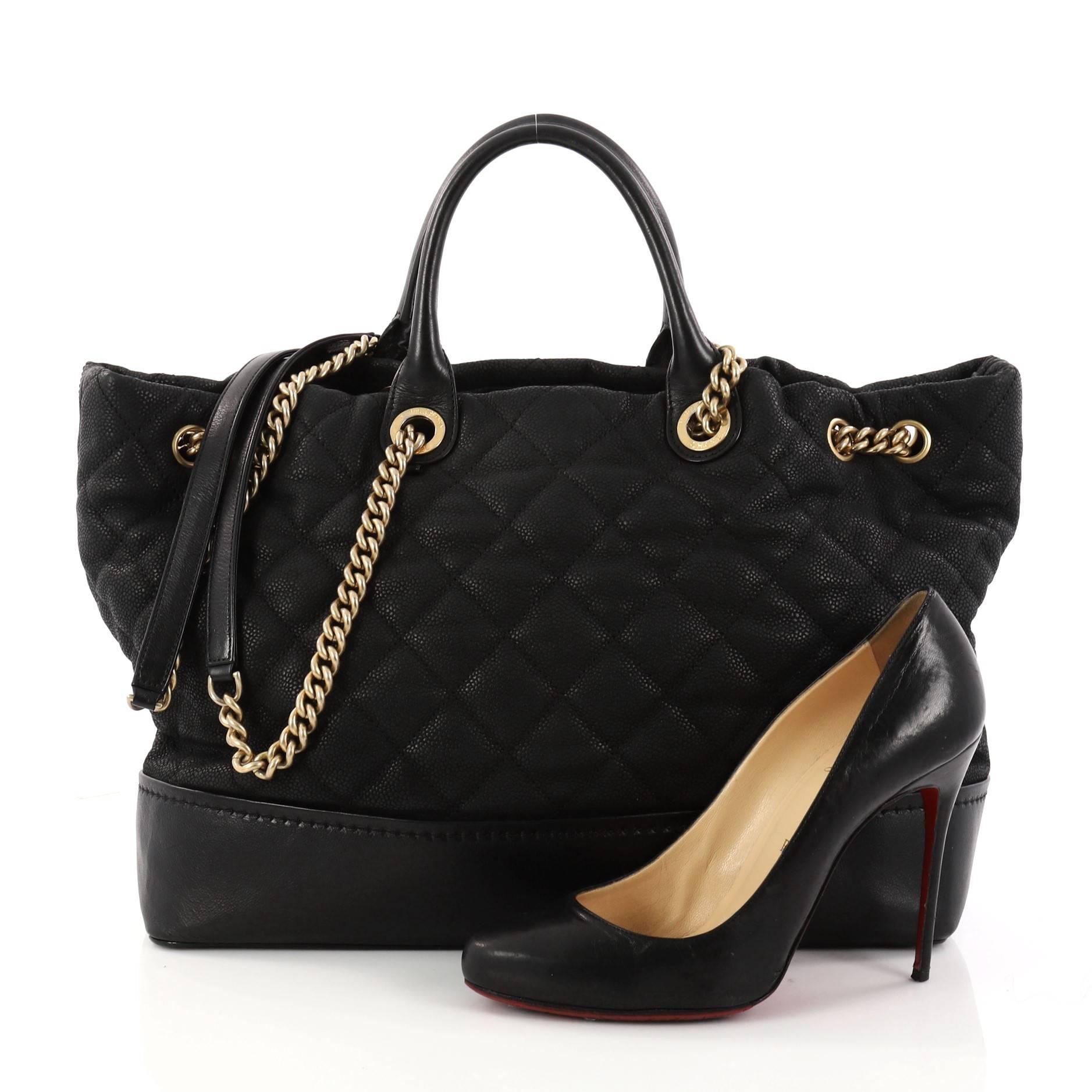 This authentic Chanel Globetrotter Drawstring Shopping Tote Quilted Iridescent Caviar Large is perfect for everyday use. Crafted in black quilted iridescent caviar leather, this stylish tote features dual-rolled leather handles, chain-link shoulder