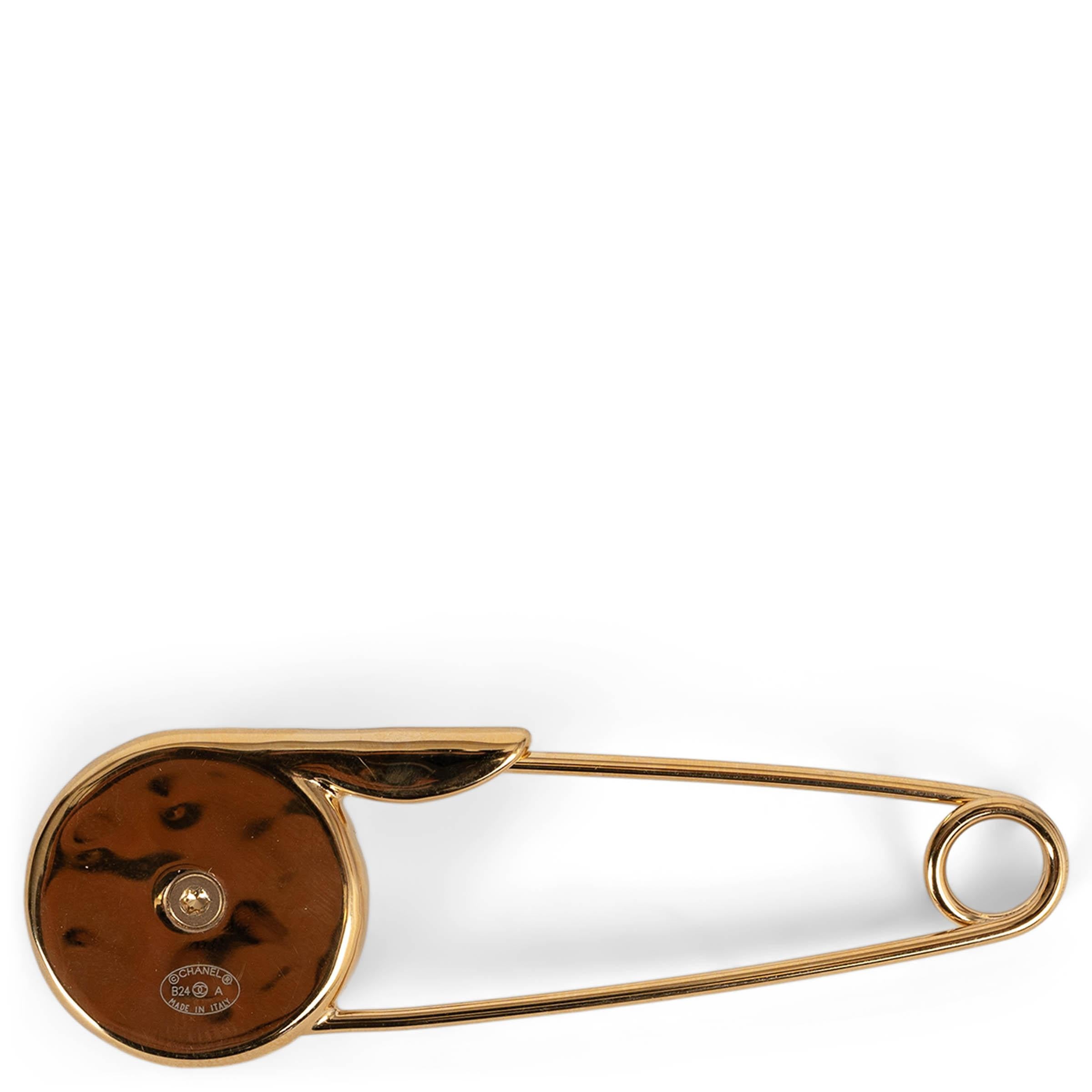 This 100% authentic Chanel safety pin brooch in gold-tone metal is a bold yet refined statement piece. Featuring a CC turn-lock detail, it is elegantly adorned with a pearly white resin cabochon pearl, adding a touch of sophistication. A unique and