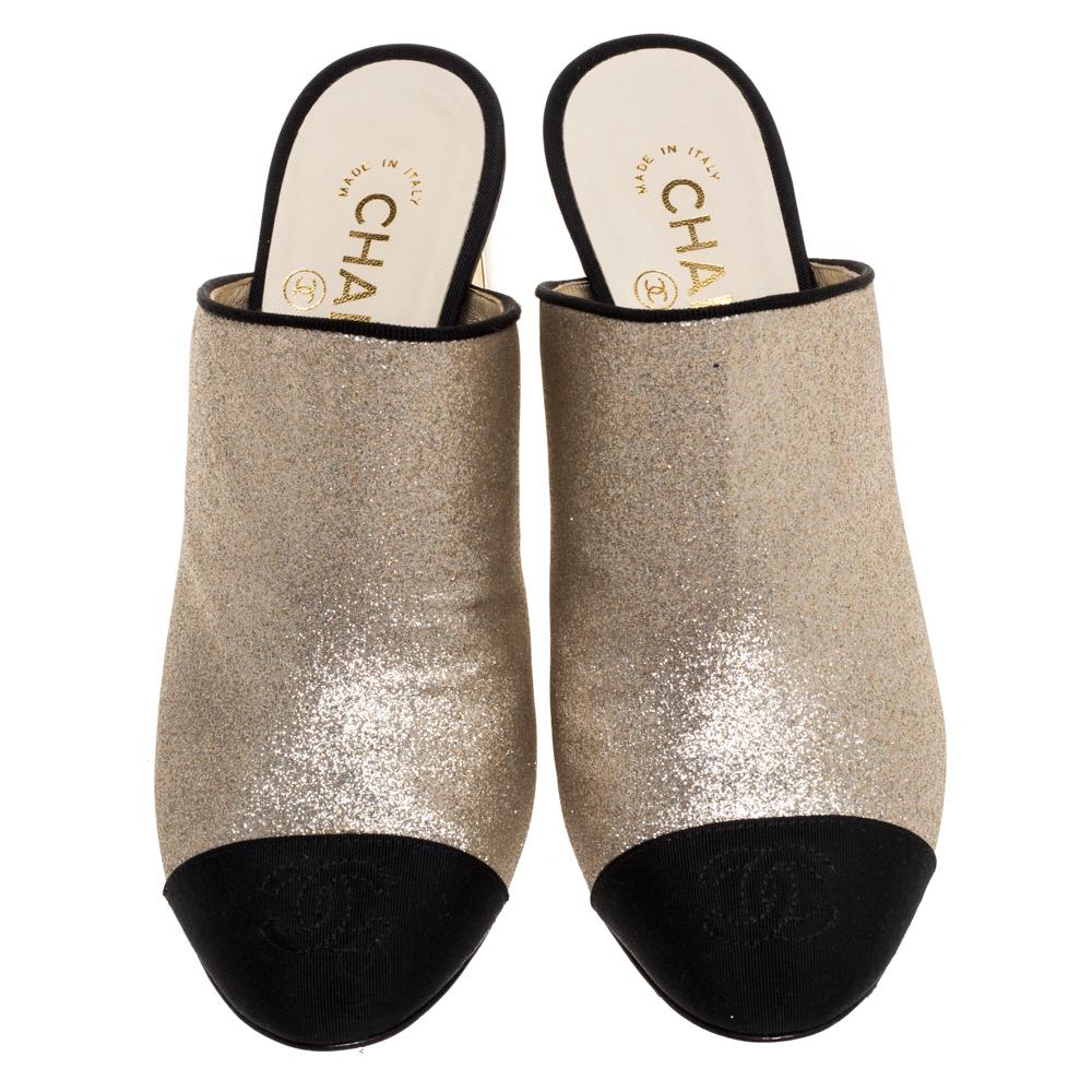 How can one not be smitten by these stunning mules by Chanel! In a magical blend of luxury and high-fashion, the mules come crafted from gold glitter leather. They are designed with black, CC-detailed cap toes and block heels accented with 'CHANEL'.