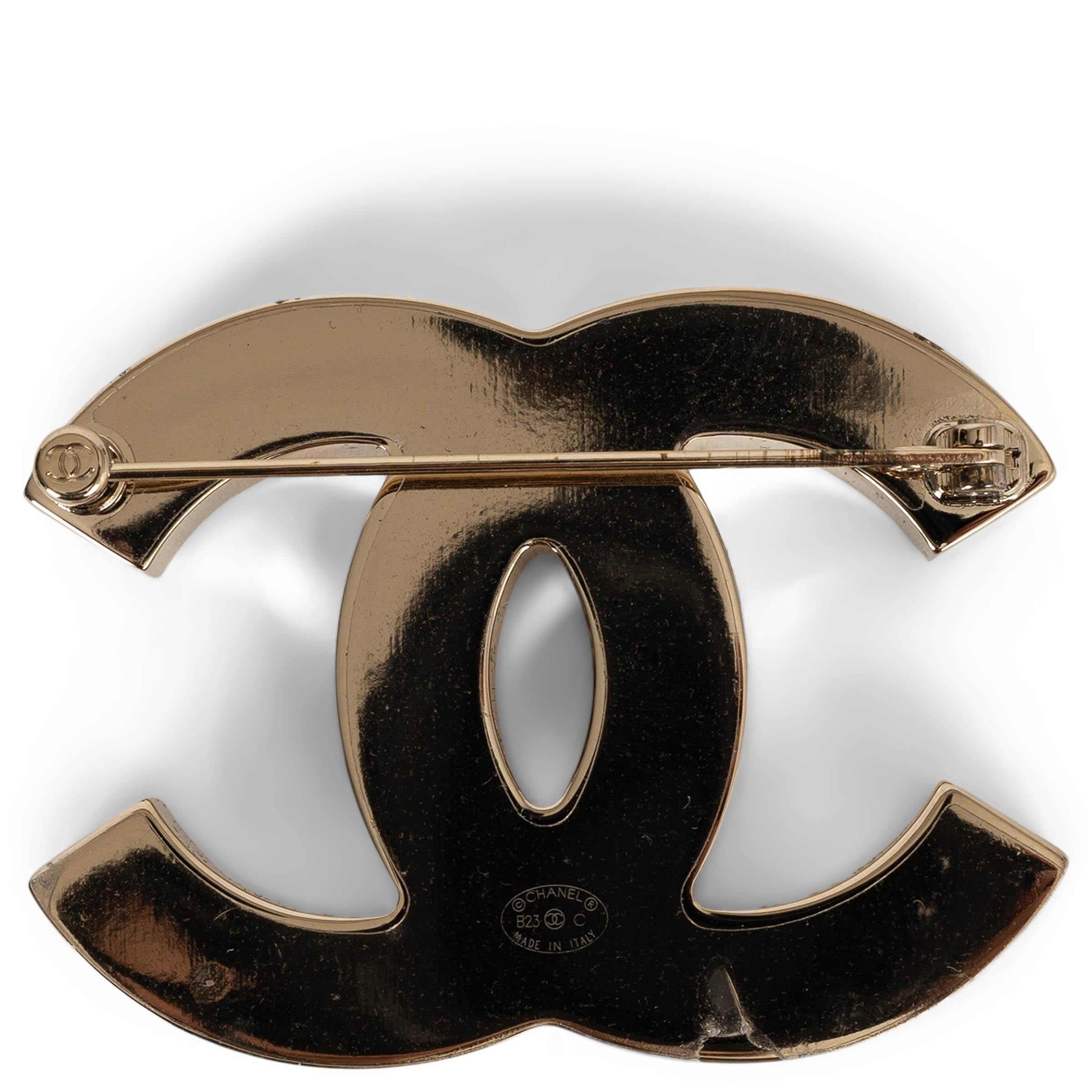 Diese 100% authentische Chanel Large CC Brosche aus goldfarbenem Metall ist von den Flaggen des Rennsports inspiriert und zeigt eine auffällige Füllung aus weißer und schwarzer Emaille in einem dynamischen Schachbrettmuster. Dieses auffällige Modell