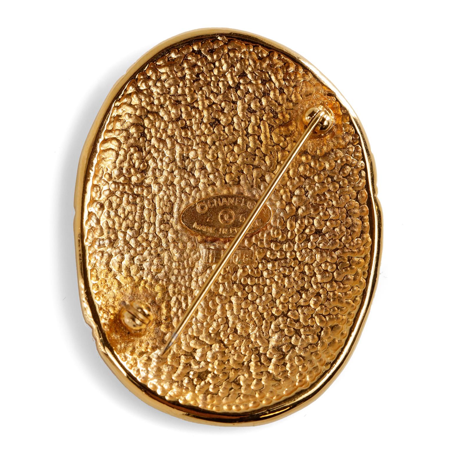 This authentic Chanel Vintage Gold CC Crown Pin is in very good condition.  Late 1980’s gold oval pin.  Interlocking CC with crown and etching.  Hinged pin on rear.  Made in France.  

