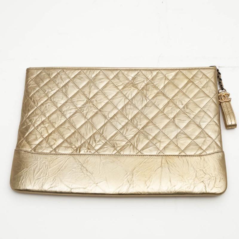 CHANEL clutch in gold aged calfskin. The small chain is made of aged silver metal, zipper with a charm at the end 