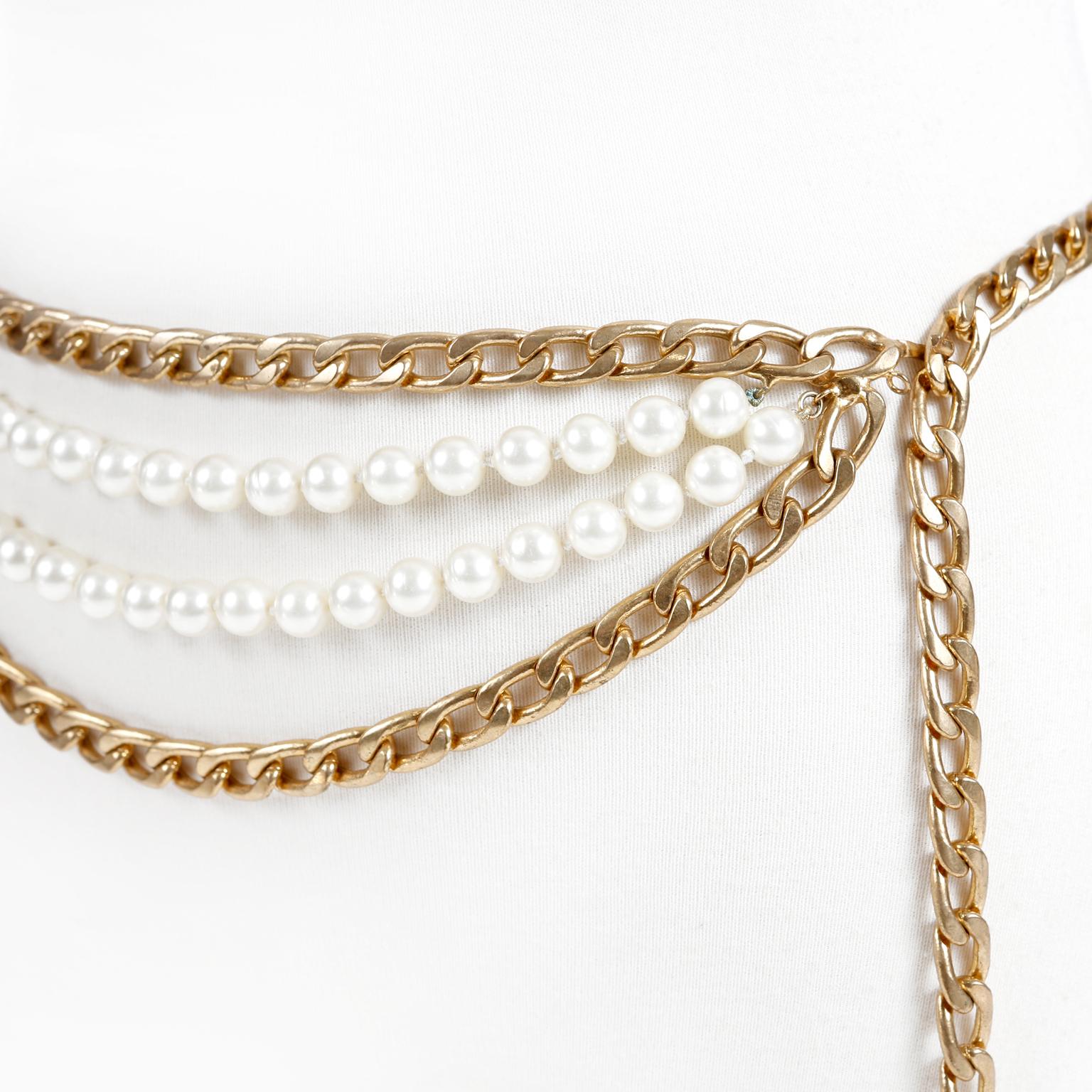 Cette authentique ceinture Chanel à double chaîne en or et pompon en perles est en excellent état.  Ce modèle très unique associe une double chaîne en métal doré à une double rangée de fausses perles. Un grand pompon en perles dorées pend à