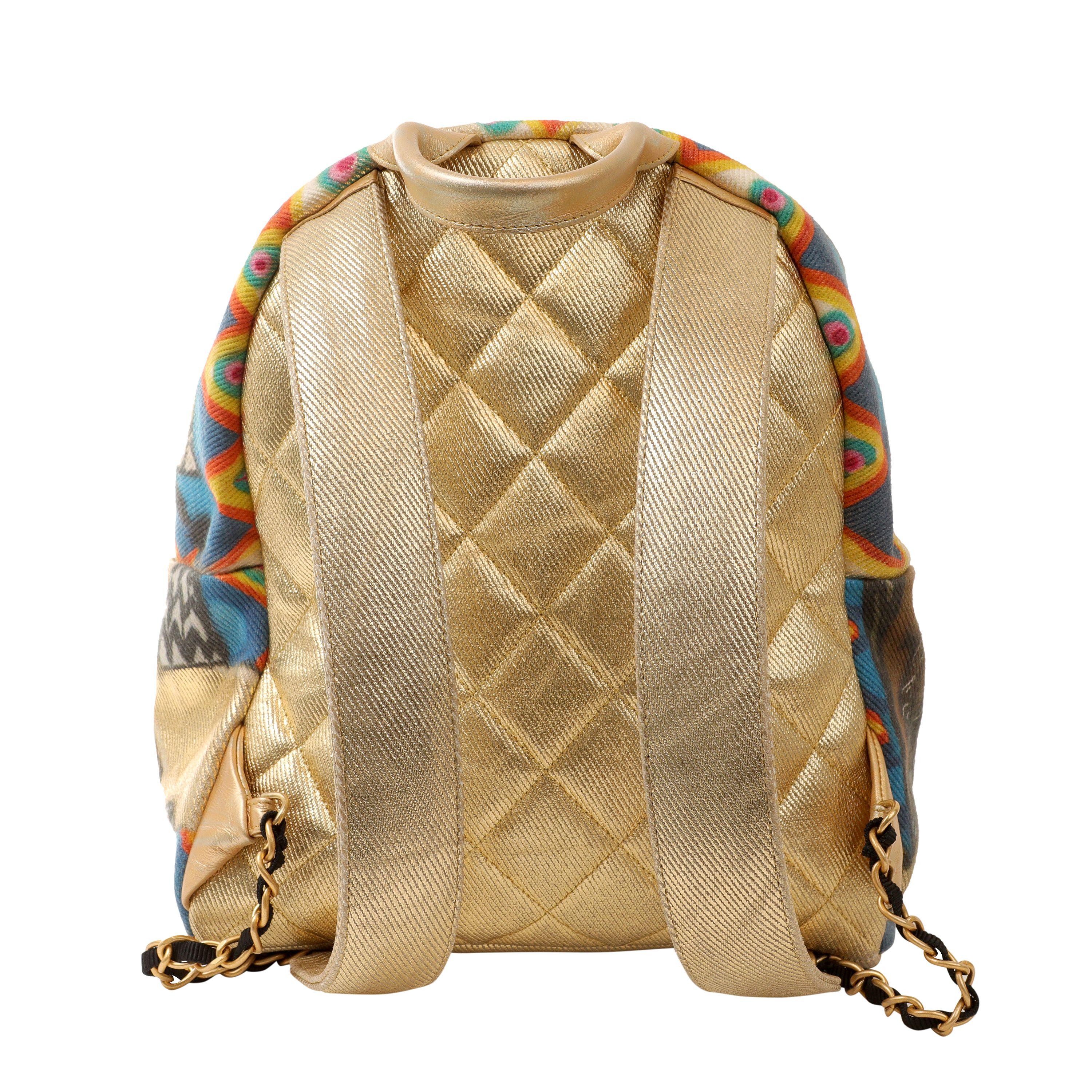 This authentic Chanel Gold Graffiti Street Spirit Backpack is in pristine condition.  Gold fabric unisex backpack with spray paint effect graffiti design.  Zippered front pouch with gold interlocking CC zipper pull charm.  Large double zippered