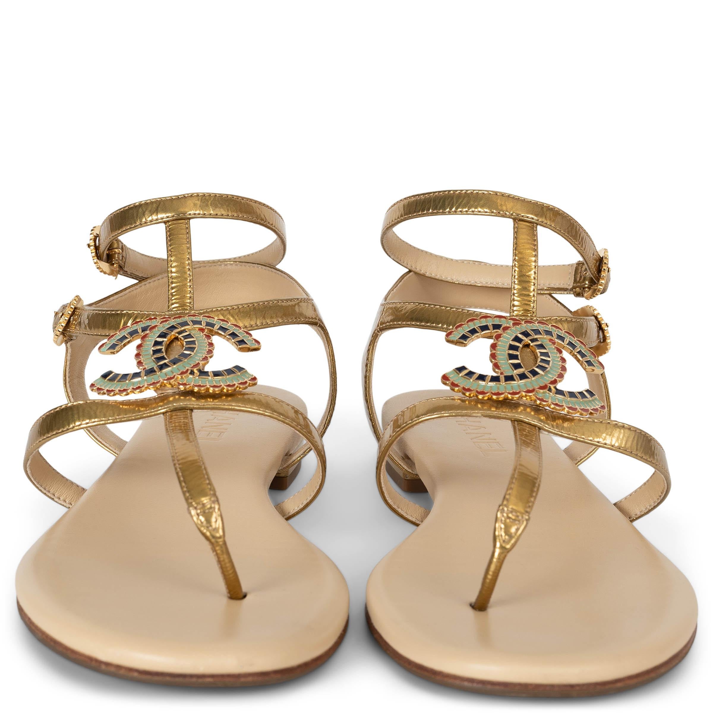 This 100% authentic Chanel T-strap thong sandals in metallic gold laminated lambskin leather channel an ancient Egyptian aesthetic with their regal gold-tone finish. Adorned with a CC logo embellished in red, mint, and navy enamel, reminiscent of