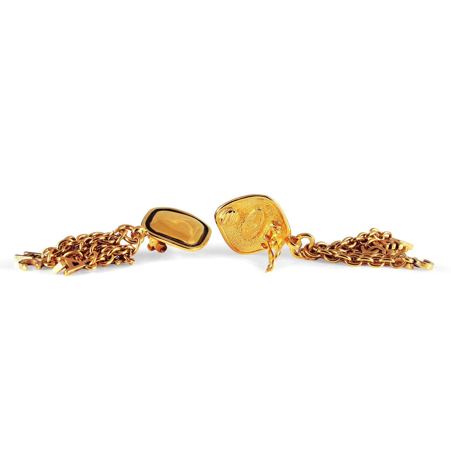Diese authentischen Chanel Gold Letter Fringe Ohrringe sind in ausgezeichnetem Zustand aus den frühen 1980er Jahren. Goldfarbene diamantförmige Clip-Ohrringe haben tropfende Ketten.  An jeder Kette baumeln Buchstabenanhänger von C H A N E L, die für