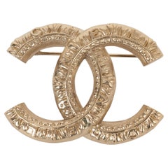 CHANEL gold metal 21A CHATEAU DES DAMES LOGO TEXTURED CC Brooch