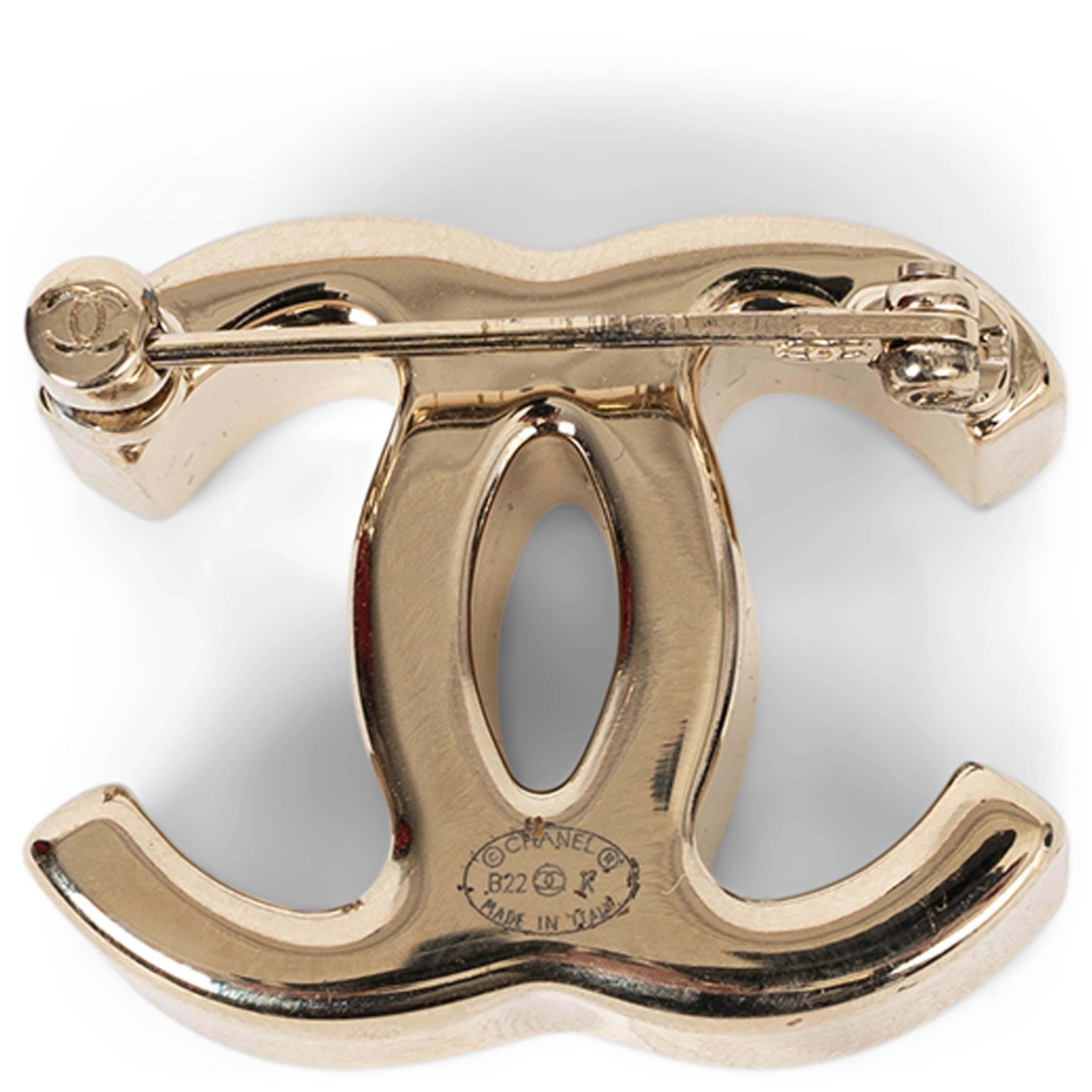 This 100% authentic Chanel brooch in beige gold-tone metal is a bold interpretation of the iconic interlocking CC logo. Designed with a thick, sculptural depth, it exudes modern elegance while maintaining the house’s timeless allure. A statement