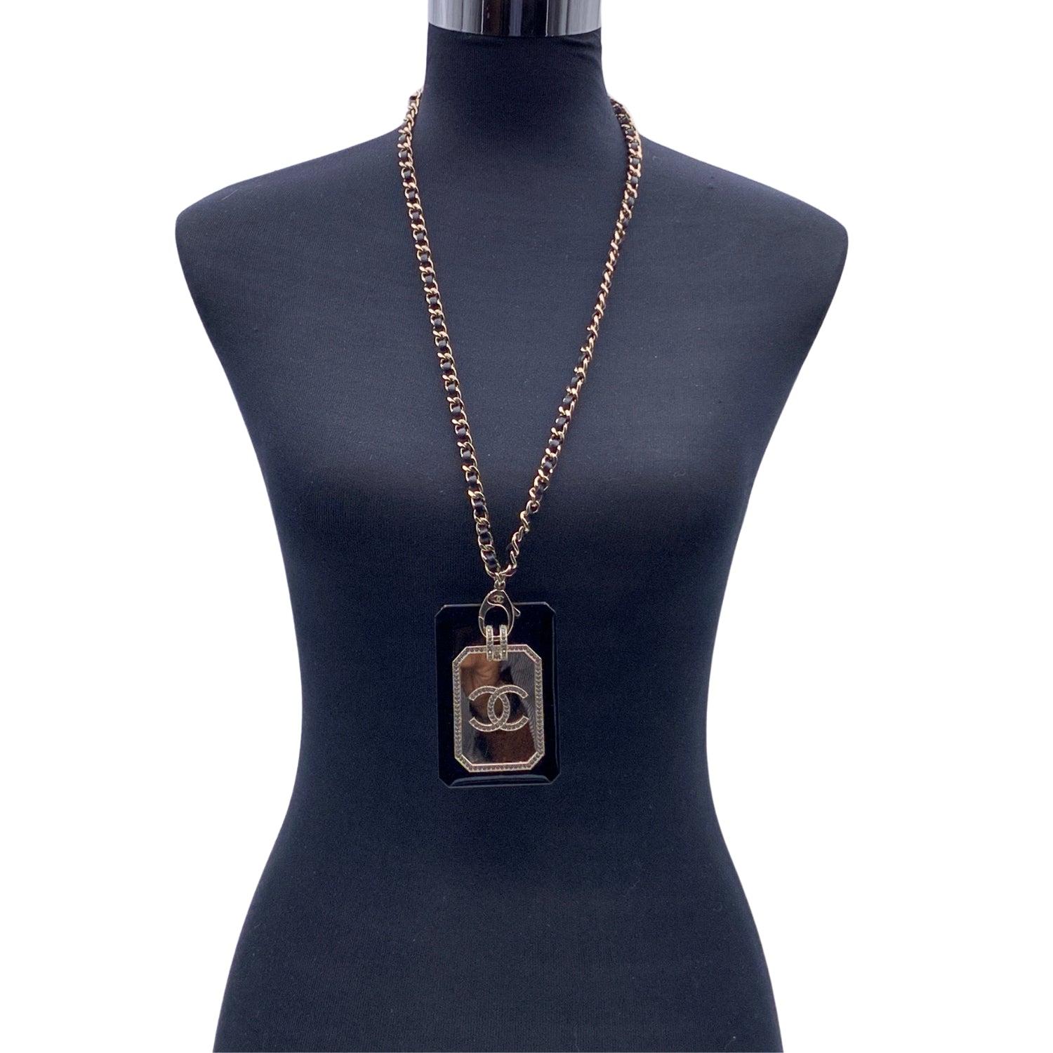 Chanel black and gold metal card case necklace. It features a crystal embellished resin card case with CC logo on the front, and a leather interwoven chain with lobster closure. Total length of the chain: 30 inches - 76.2 cm. 'Chanel B21 CC A - Made