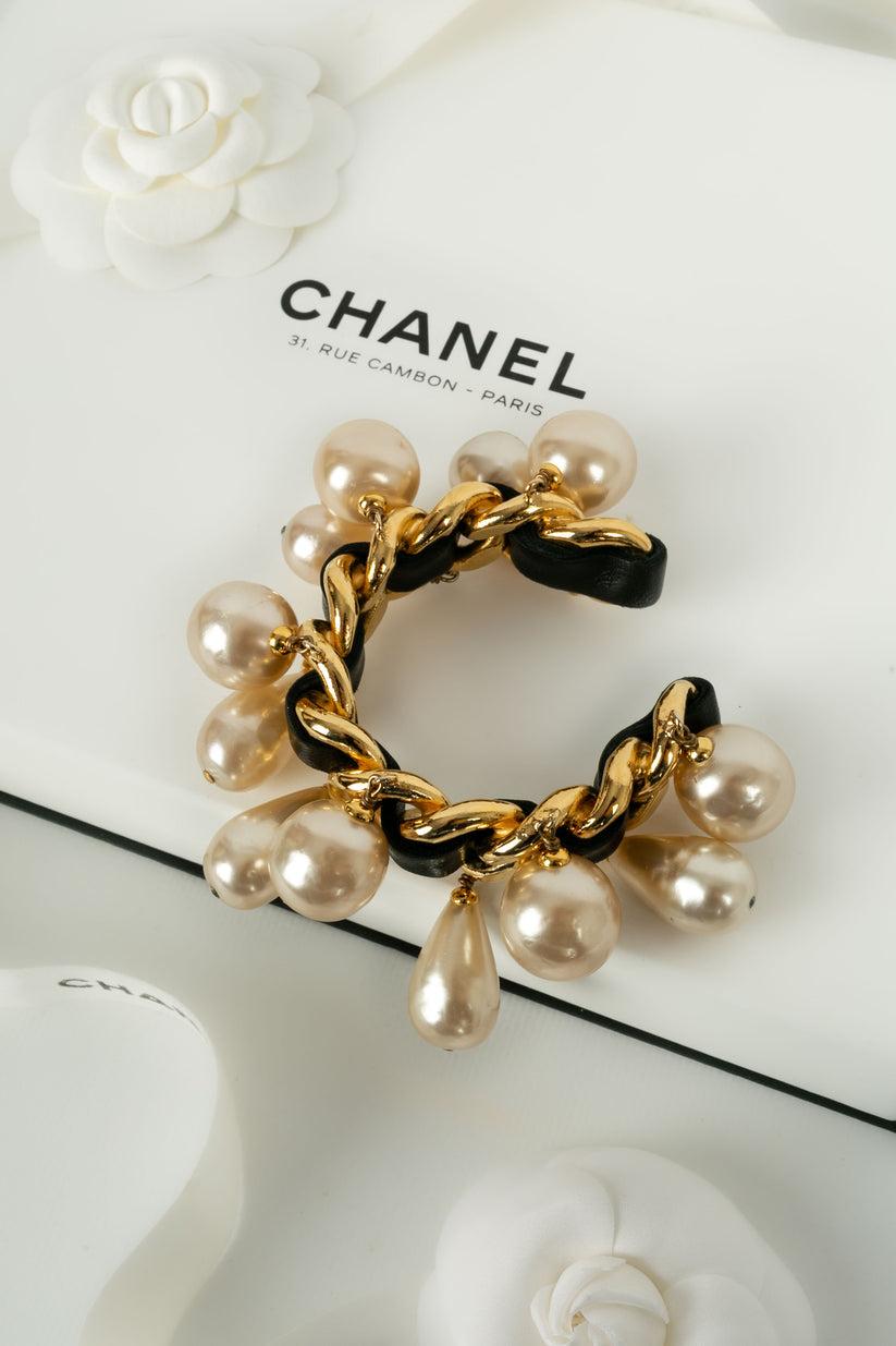 Chanel - (Made in France) Bracelet in gold metal and black leather, holding costume pearly beads. 2cc3 Collection.

Additional information:

Dimensions: 
Length: 14 cm
Opening: 2 cm

Condition: 
Very good condition

Seller Ref number: BRAB136