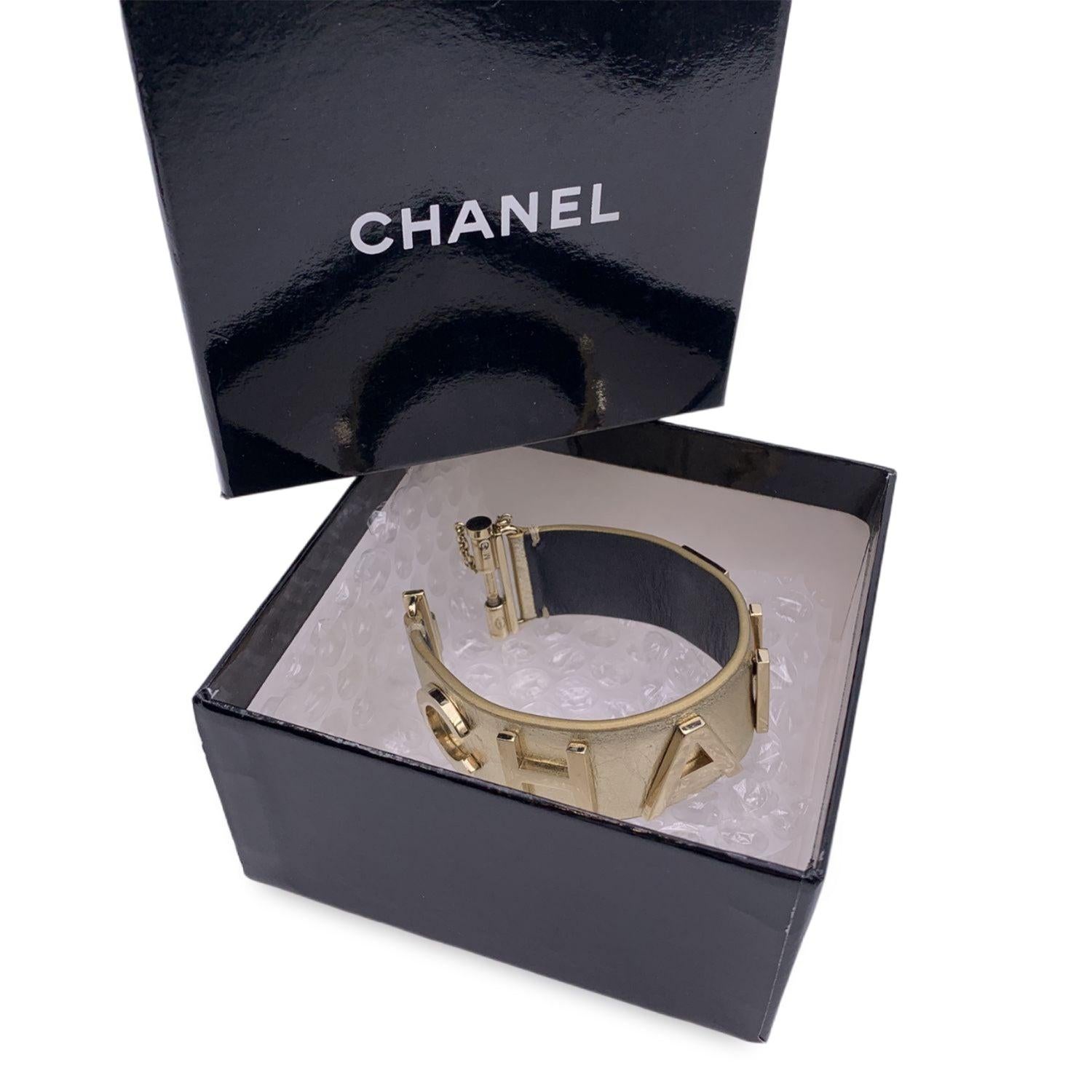 Lovely bracelet by CHANEL, crafted of gold metal leather . It features gold metal CHANEL lettering. Slide closure 'Chanel B18 CC B Made in Italy' oval hallmark near the closure. Size M. Total lenght: 7 inches - 17.8 cm. Height: 1 inch - 2.5 cm
