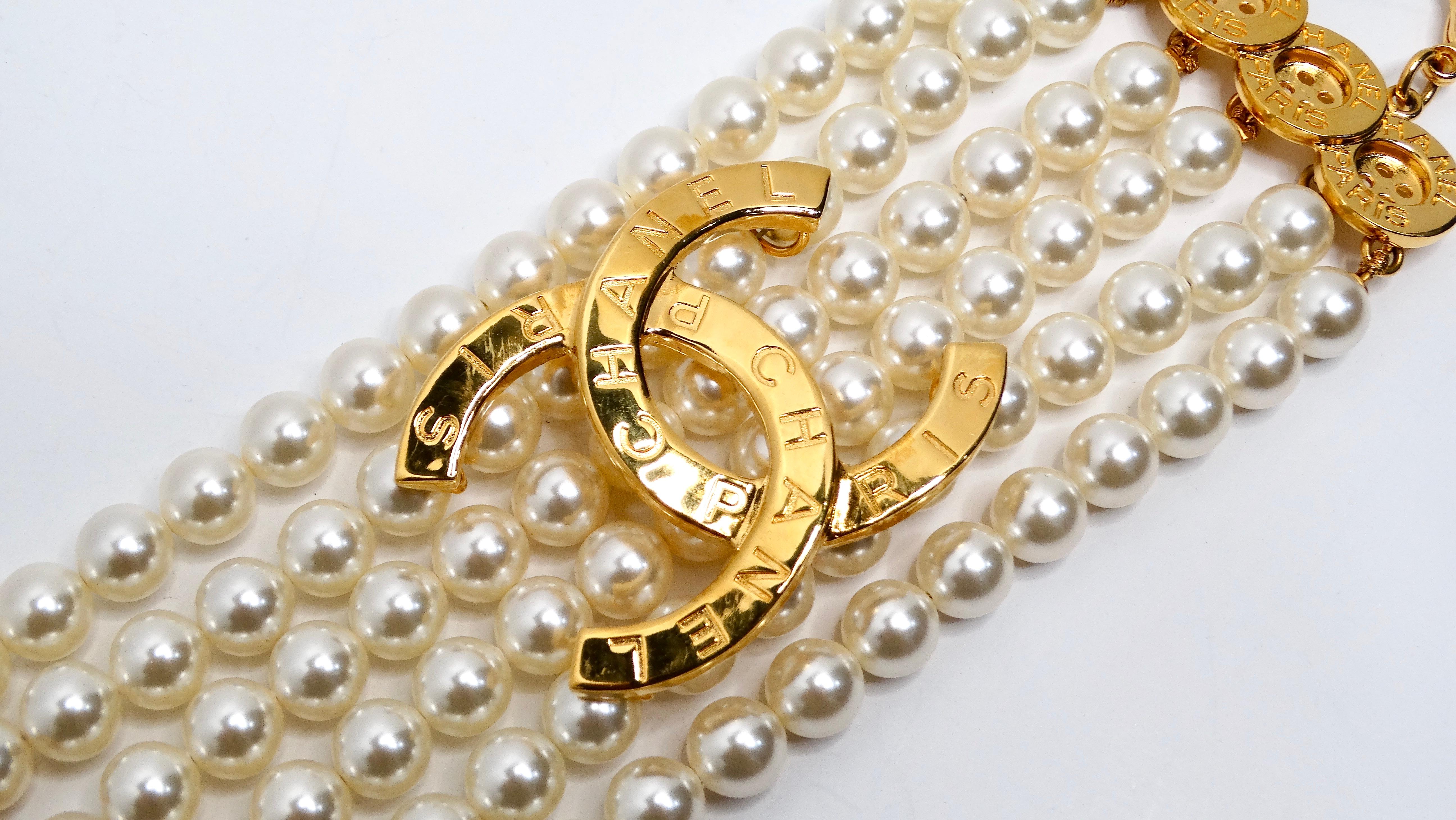 The Chanel Gold Plated CC & Button Detail 6-Strand Pearl Bracelet is a luxurious accessory that epitomizes timeless elegance. This exquisite piece features six strands of lustrous pearls elegantly connected into a cohesive bracket, creating a