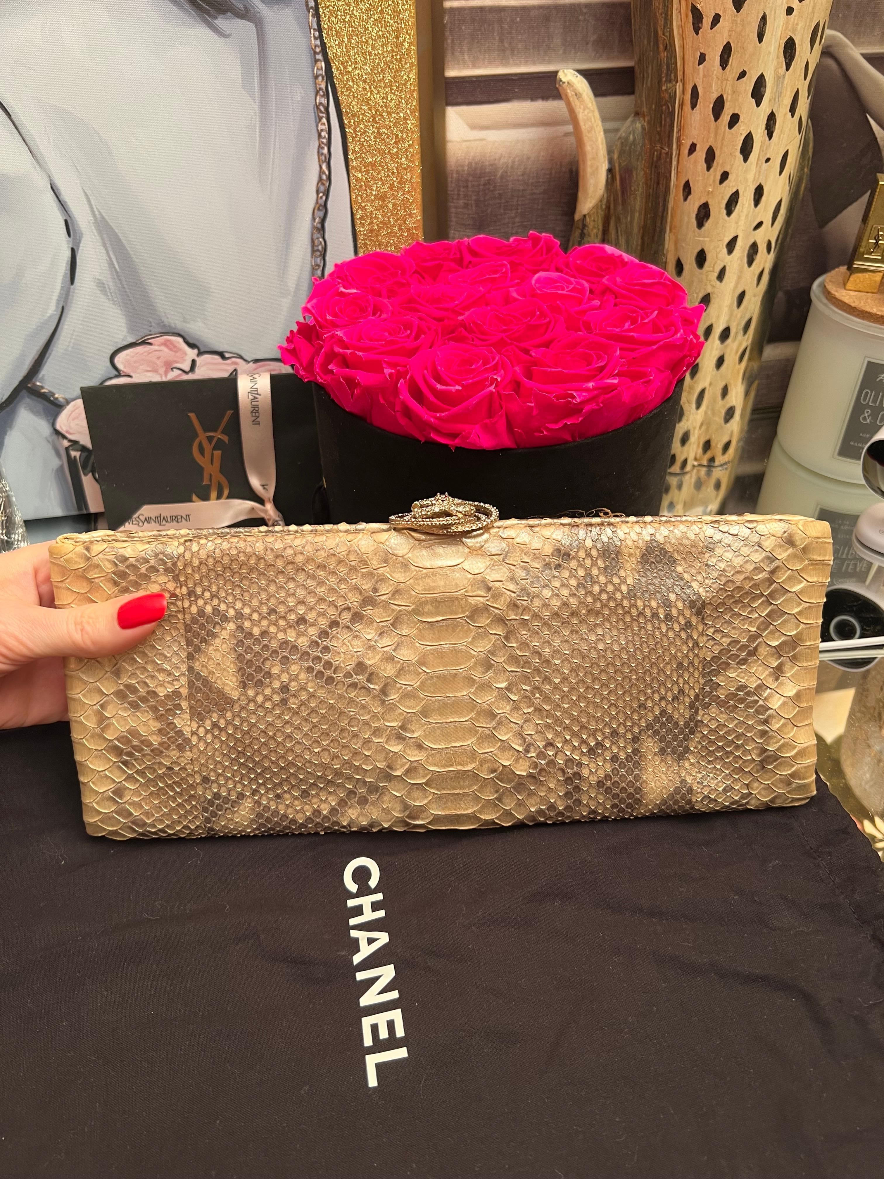 Rare édition limitée de la pochette Chanel en python beige doré avec fermoir CC et camélia en cristal. Deux compartiments à enfiler et un compartiment principal avec fermeture à fermoir camélia. Doublé de satin doré, il est doté d'une pochette et