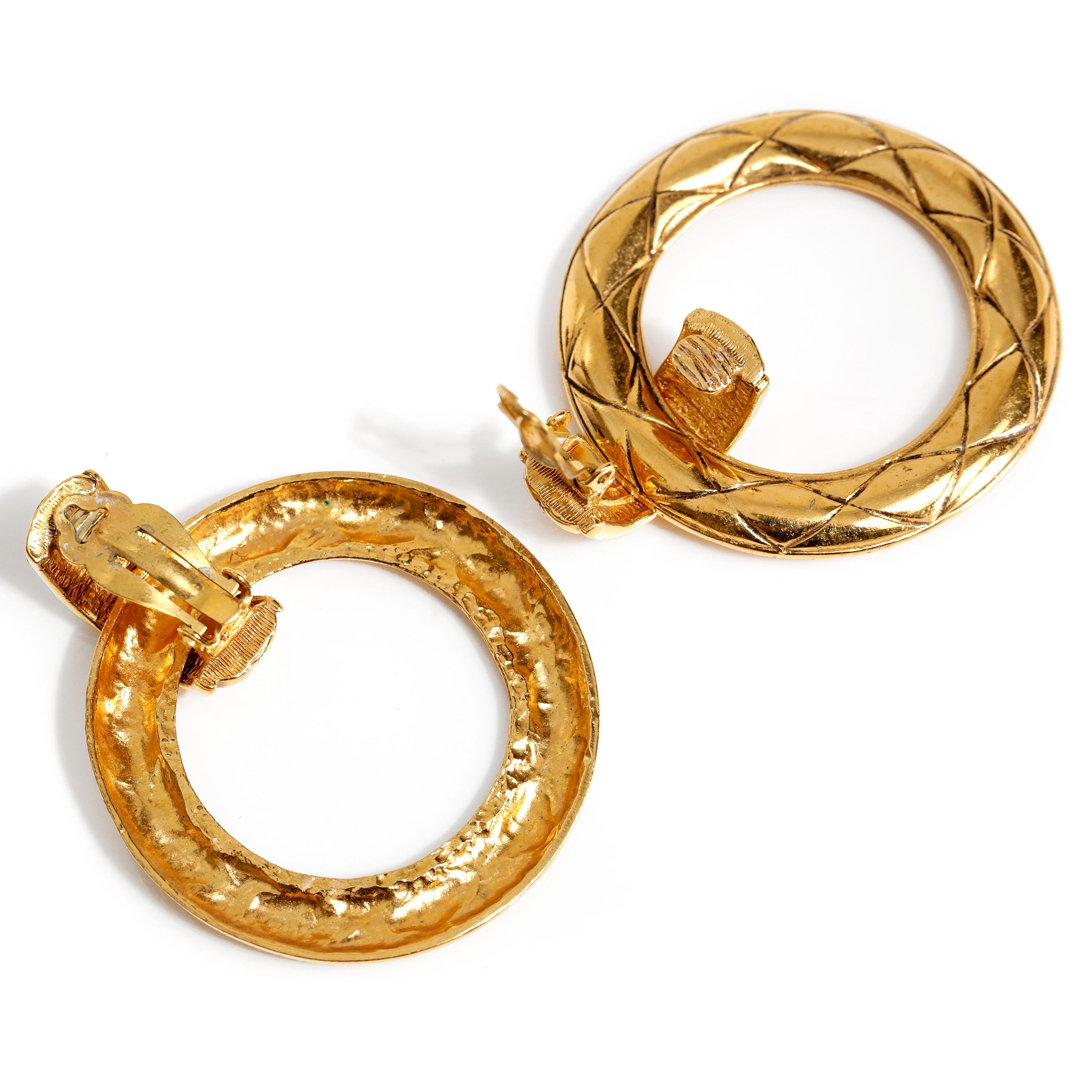 These authentic Chanel Gold Quilted Hoop Earrings are in excellent vintage condition.  Round gold hoop dangles from a small demi hoop.  Etched with signature Chanel quilted pattern.   Clip on closure.  
Approximately 2”x 2”

