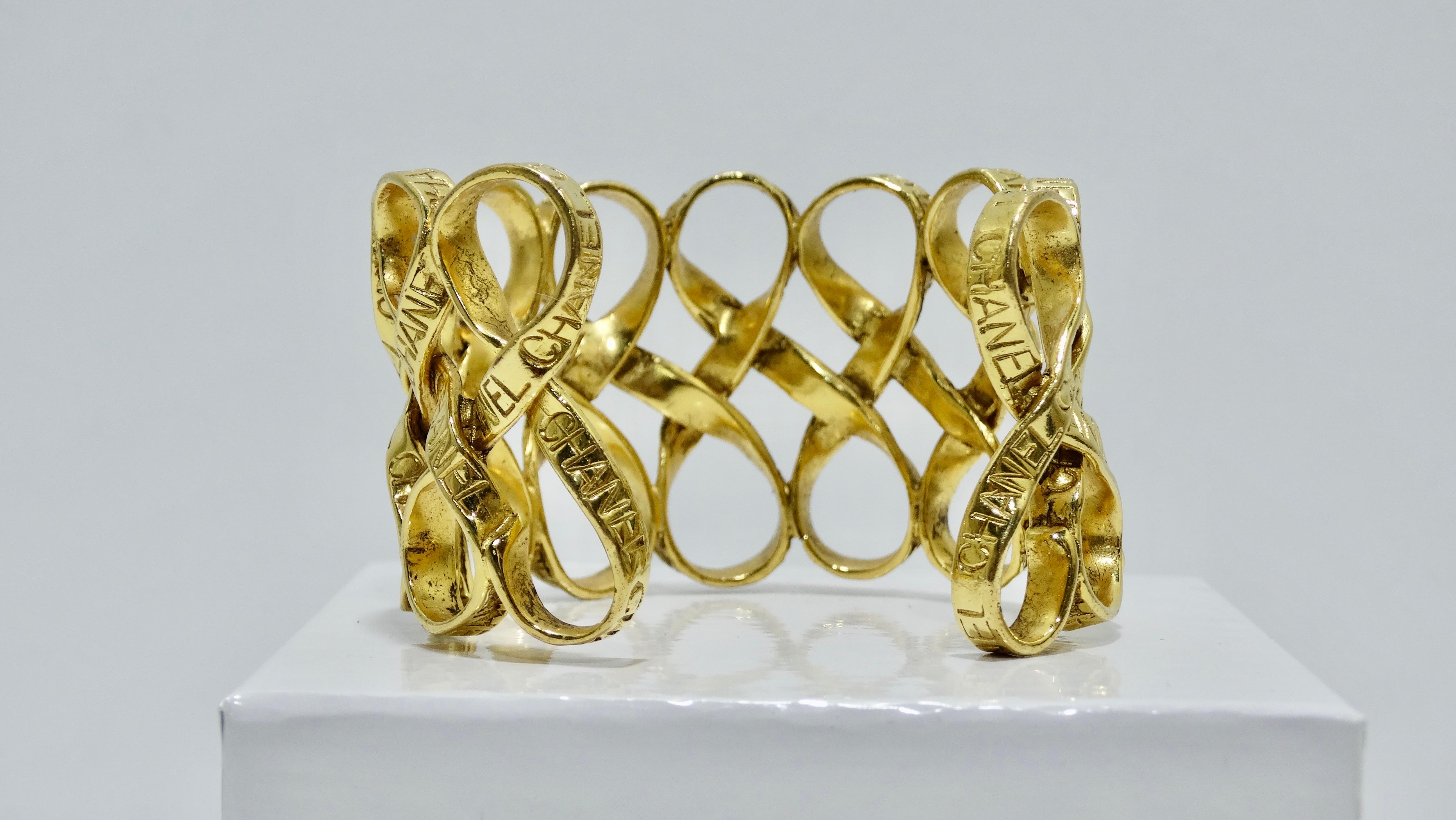 Can you say 'Classic?' Circa late 1960s early 1970s, this stunning gold plated Chanel cuff features a ribbon motif throughout and is repeatedly embossed with 'Chanel'. This cuff features an open backing for easy wear. This piece is extremely