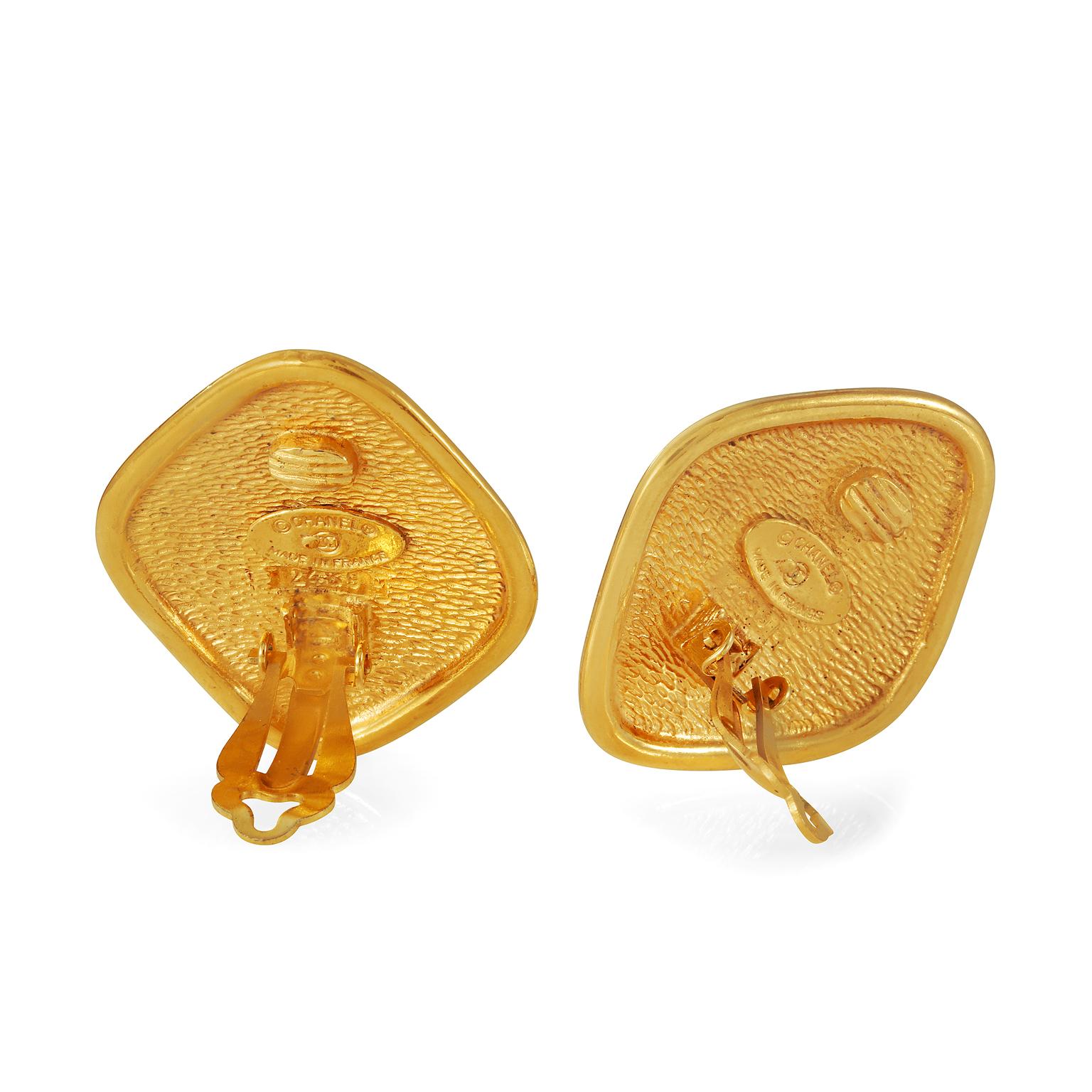 These authentic Chanel Gold RUE CAMBON Earrings are in excellent vintage condition from the early 1980’s. Gold diamond shaped clip on earring is etched with CHANEL 31 RUE CAMBON lettering and an interlocking CC.  Clip on closure. Made in France. 