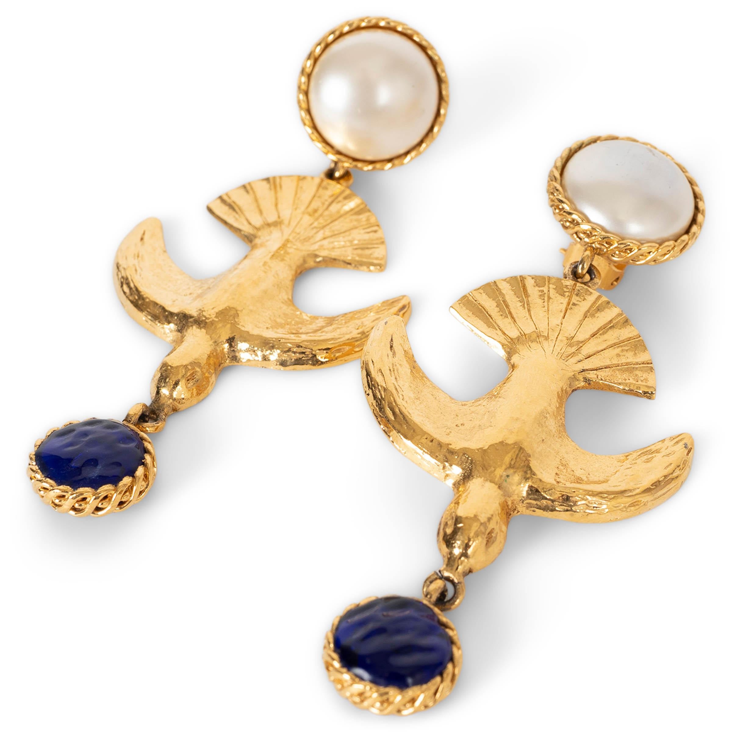 These 100% authentic Chanel clip-on earrings feature a luminous pearly white imitation pearl cabochon leading to a sculpted gold-plated bird motif, finished with a royal-blue Gripoix glass bead. A striking, museum-worthy design that embodies