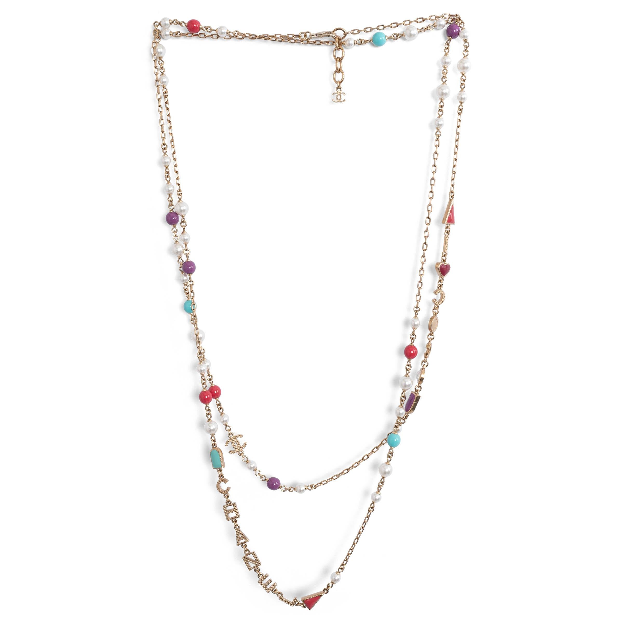100% authentic Chanel faux pearl necklace in gold-tone brass. Detailed with an array of purple, pink, white  and turquoise faux pearls with detailing COCO CHANEL name through out the necklace. Has bee carried once and is in virtually new condition.