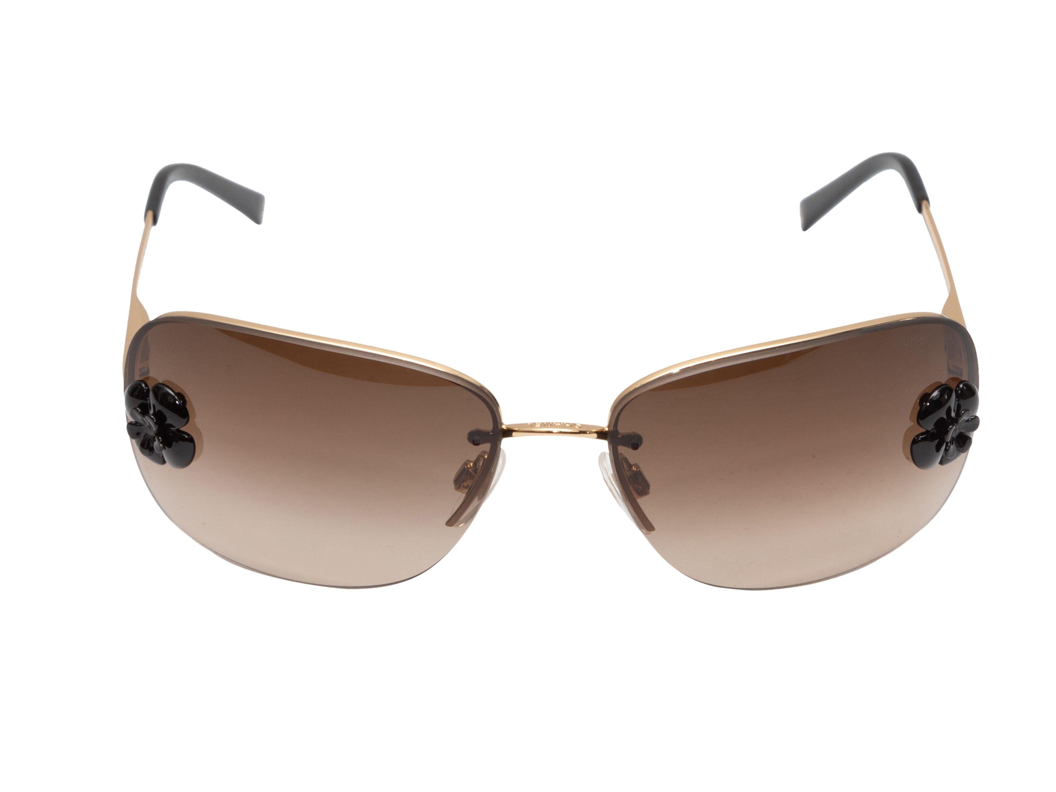 Product Details: Gold-tone metal rectangular sunglasses by Chanel. Brown tinted lenses. Black camellia accents at temples. 1.75