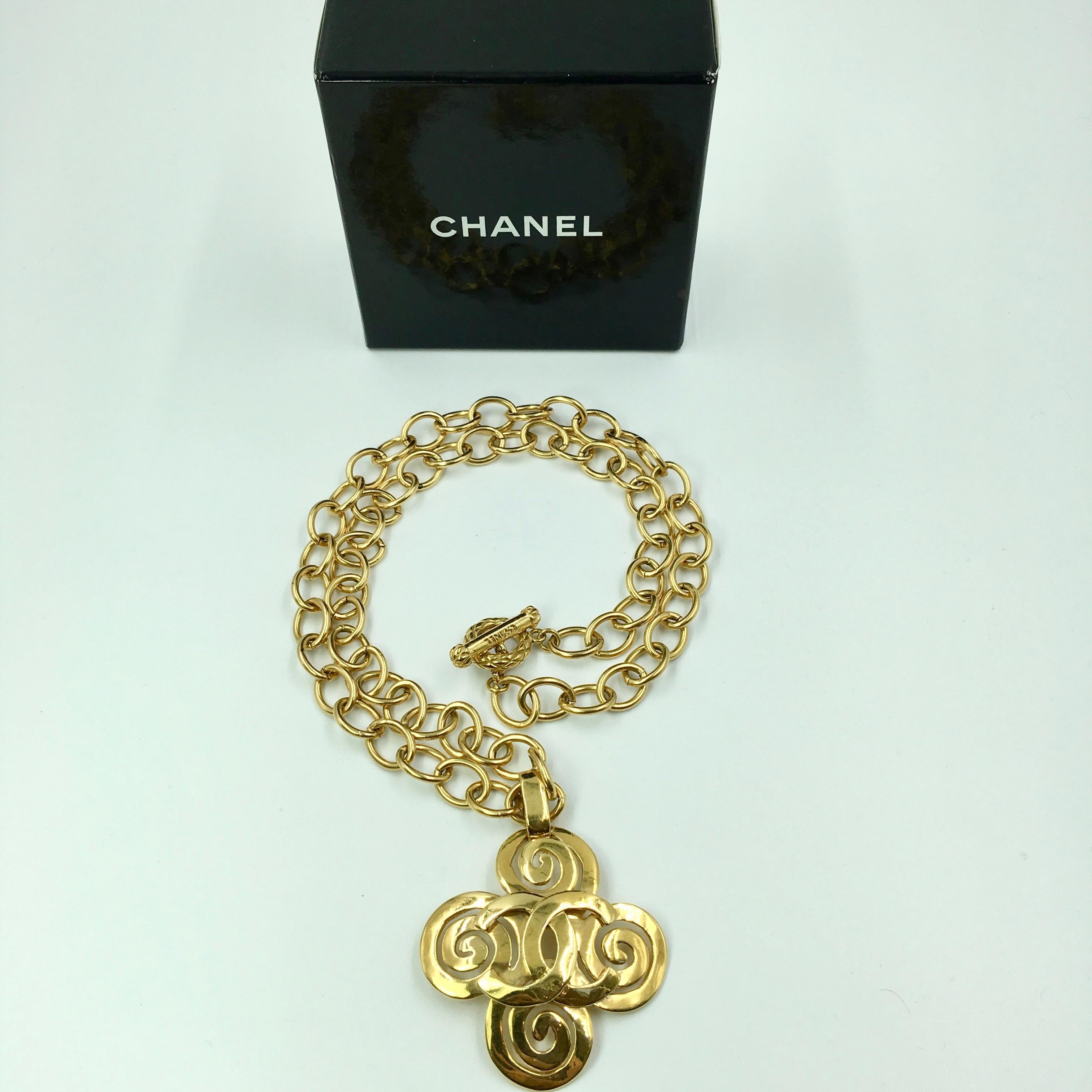 Chanel Gold Tone CC Logo Swirl Cross Necklace. Stamped Chanel and Made In France. 
Good vintage condition. One chain link has a slight discoloration. It is not noticeable when worn. Please see last photo. 

Measurements are as follows:

Necklace