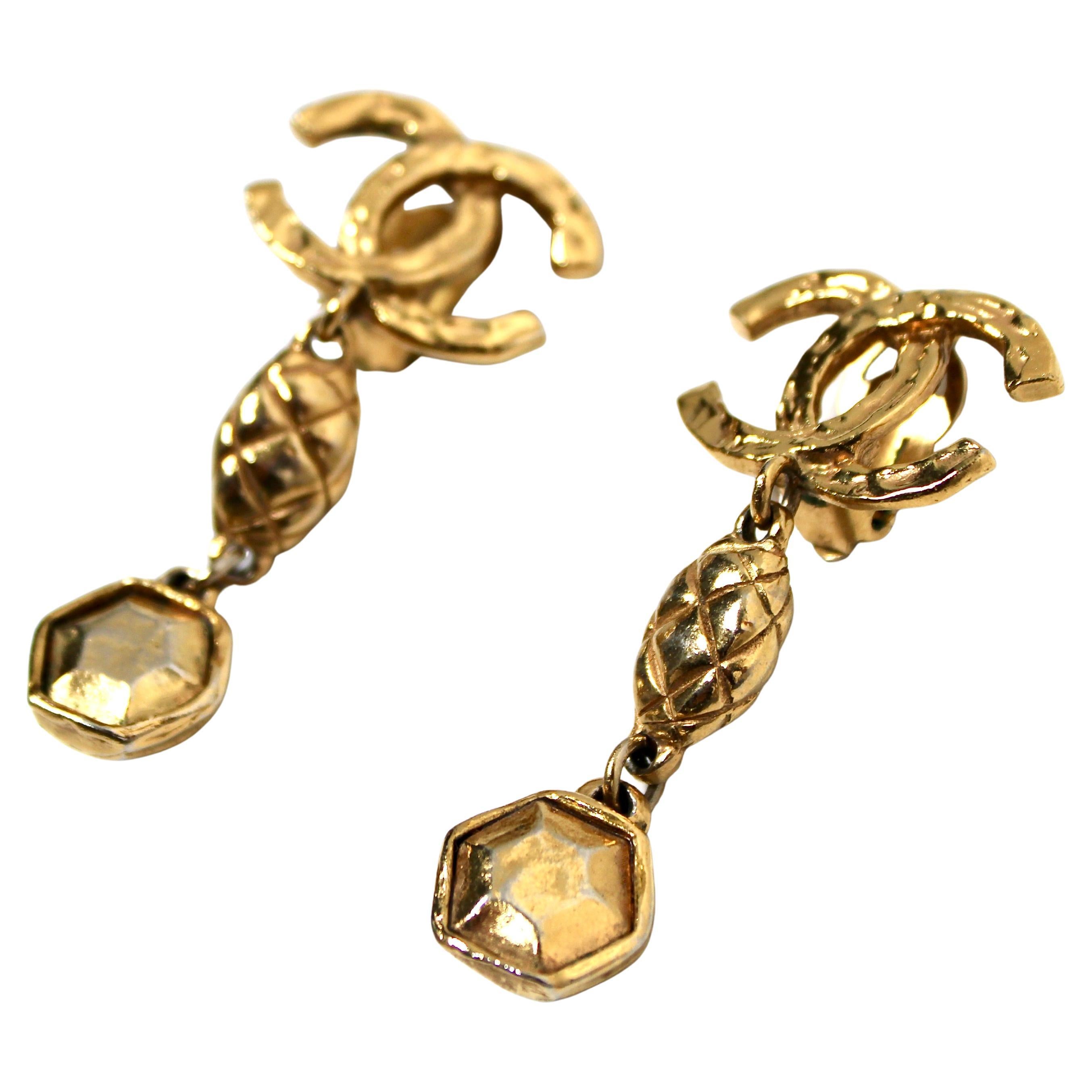 Gli orecchini a goccia Coco Chanel in oro, risalenti agli anni '80 circa, sono uno splendido esempio di gioielleria vintage. Questi orecchini, caratterizzati dall'iconico logo CC a incastro posto in alto, emanano un'eleganza e una raffinatezza senza