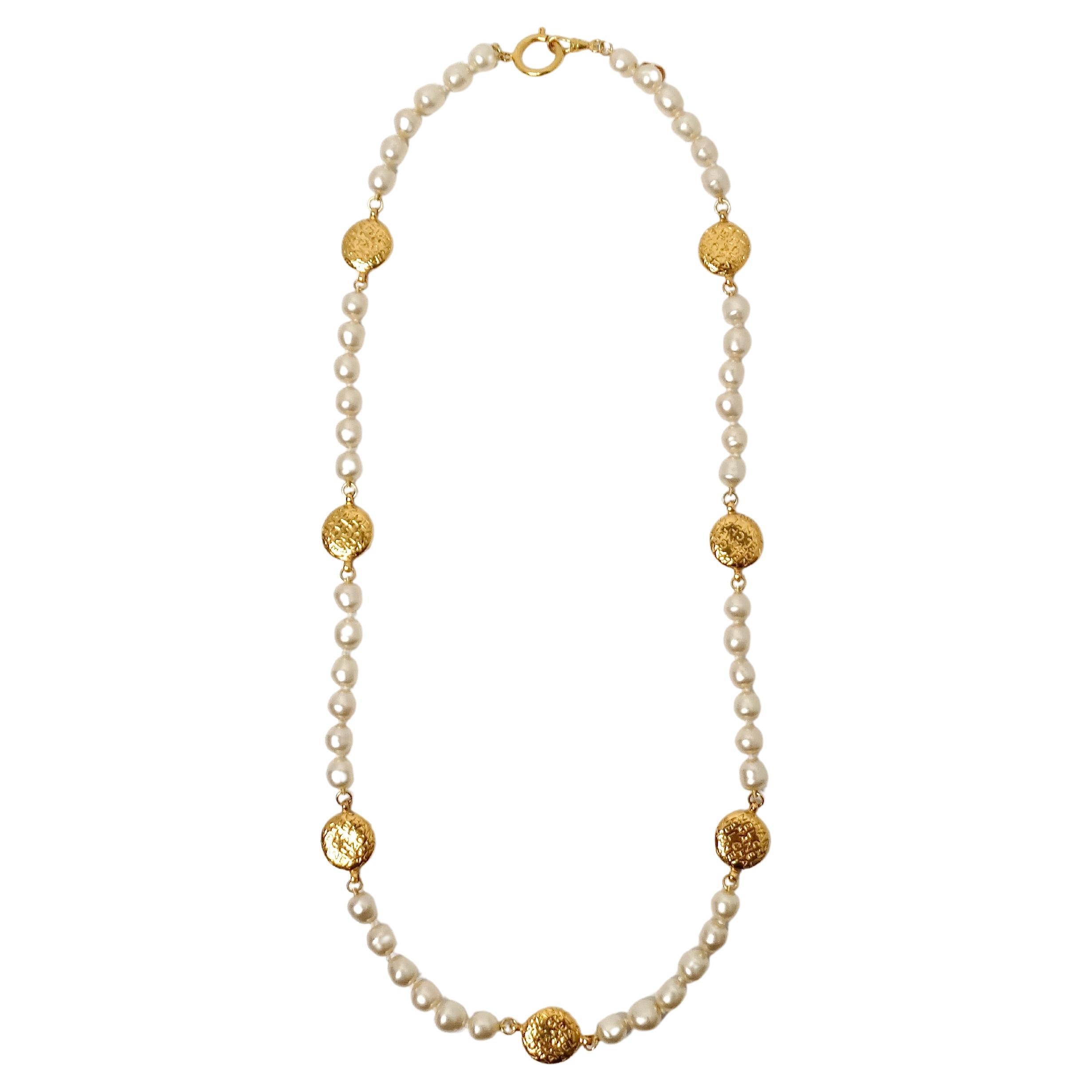 Le collier Chanel à pièces de monnaie et perles fantaisie en or est un accessoire étonnant qui allie sans effort l'élégance intemporelle au style contemporain. Confectionné avec des perles fantaisie lustrées, ce collier respire la sophistication,