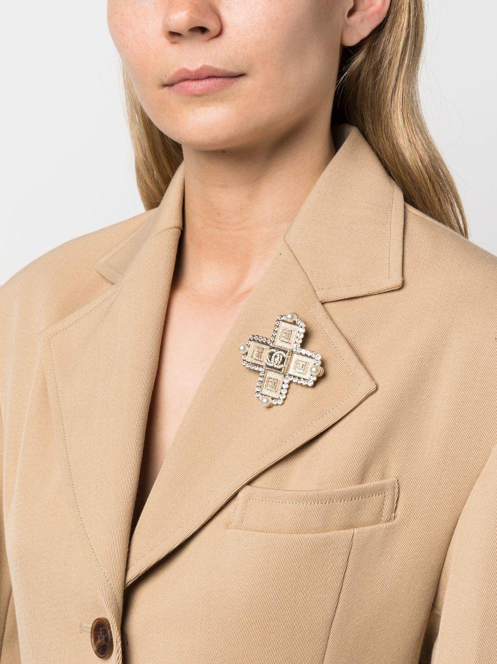Chanel 2000s CC rhinestone-embellished cross brooch featuring gold-plated hardware, a cross motif, a signature interlocking CC logo, rhinestone embellishment, faux-pearl embellishment, a pin fastening, a back plaque.
Circa 2000s . Made in