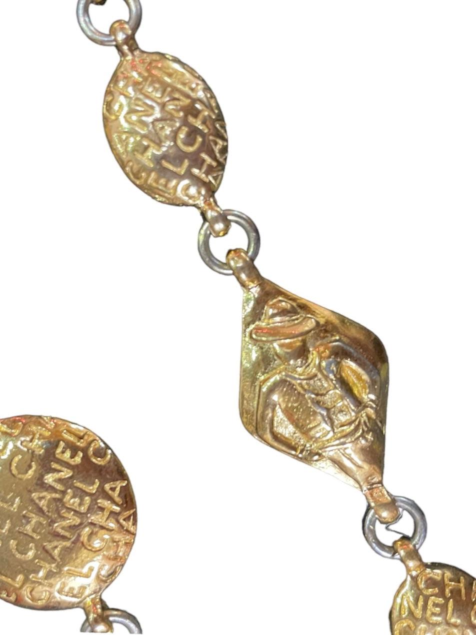 Cette demi parure Chanel vintage des années 1980 présente le logo en relief et un portrait de Coco Chanel sur un long collier de 34 pouces et des boucles d'oreilles assorties. Il s'agit d'une pièce classique et intemporelle qui deviendra à coup sûr