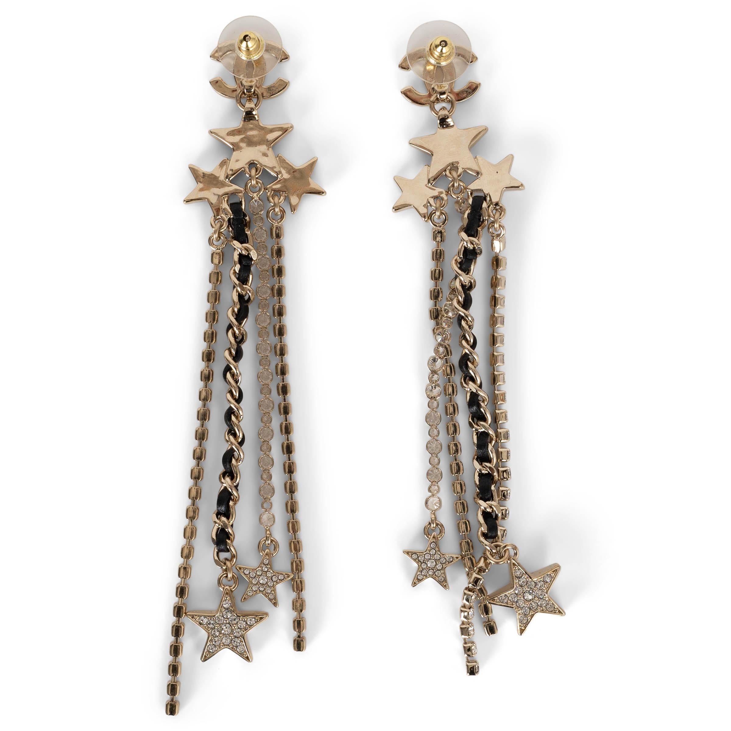 These 100% authentic Chanel pendant earrings in light gold-tone metal exude elegance with a clear crystal-encrusted CC logo and three sparkling stars at the top. Dangling below are three delicate crystal strands intertwined with the house’s