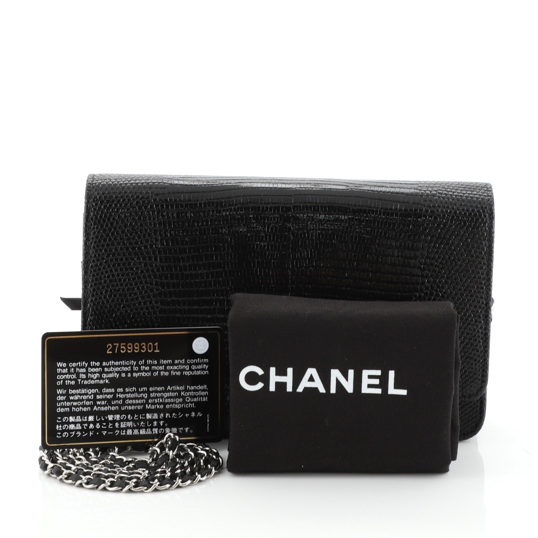 This Chanel Golden Class Wallet on Chain Lizard Embossed Leather, crafted from black lizard embossed leather, features woven-in leather chain straps and silver-tone hardware. Its CC flip clasp closure opens to a black fabric and leather interior