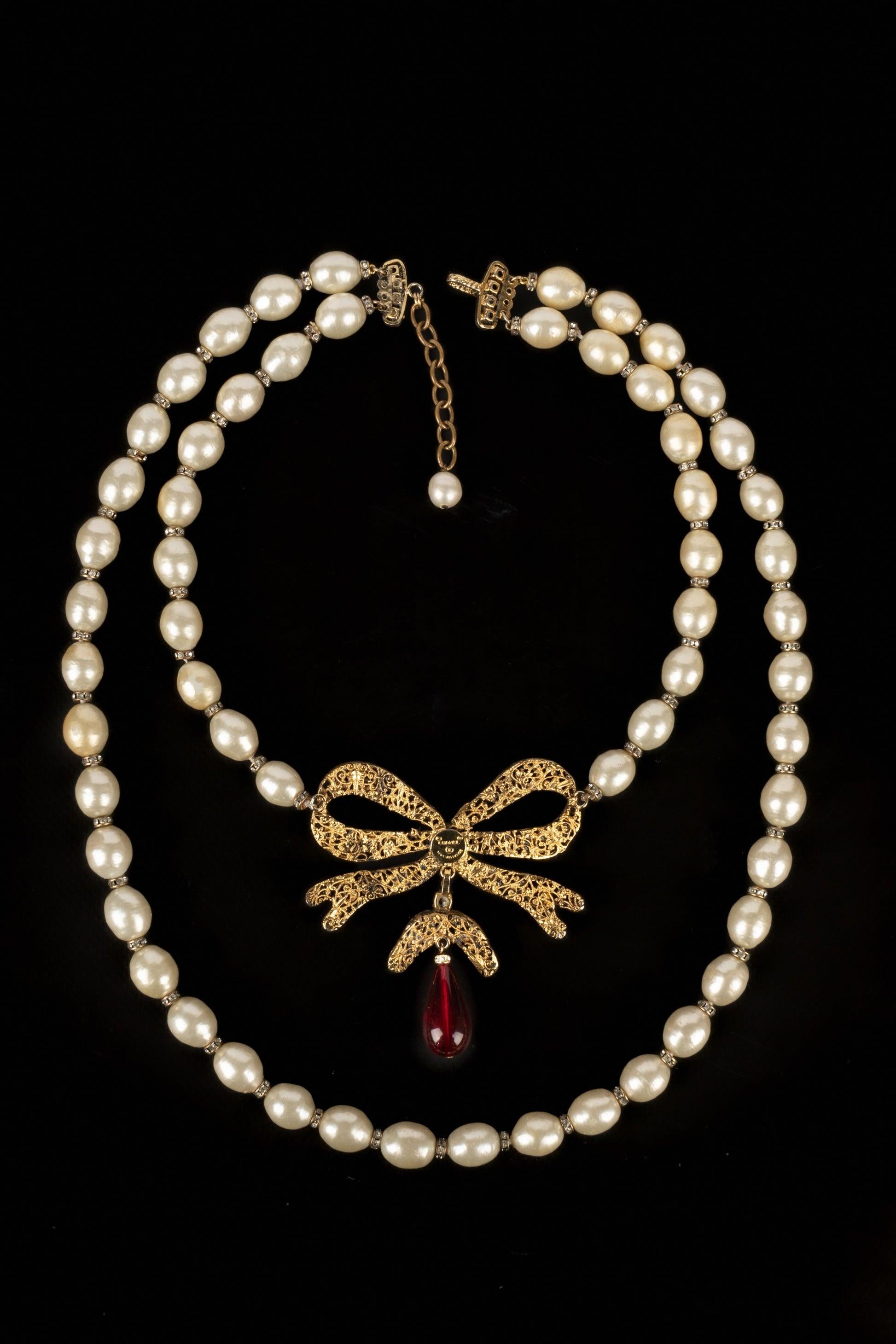 Chanel - (Made in France) Golden metal necklace with costume pearls, rhinestones, and red glass paste. To be mentioned, some pearls have areas without the pearly material.

Additional information:
Condition: Good condition
Dimensions: Length: from