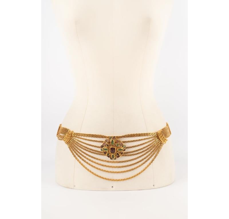 CHANEL - (Made in France) Multi-row golden metal chain belt ornamented with a golden metal pendant brooch with glass paste. Belt from the 1996 Fall-winter collection, brooch from the 1998 Fall-winter collection.

Additional information:
Condition: