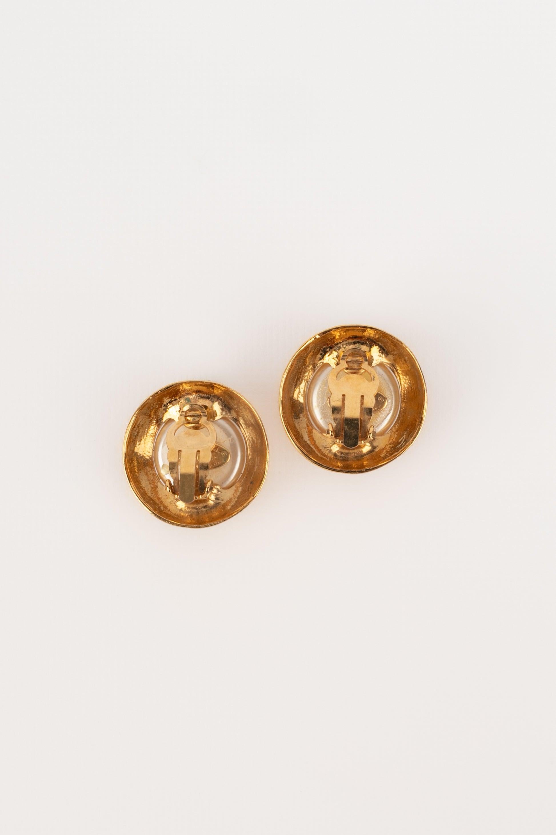 Chanel - (Made in France) Orecchini a clip in metallo dorato con cabochon di perle in costume. Collezione Primavera-Estate 1993.

Informazioni aggiuntive:
Condizioni: Ottime condizioni
Dimensioni: Diametro: 3 cm
Periodo: 20° secolo

Riferimento del